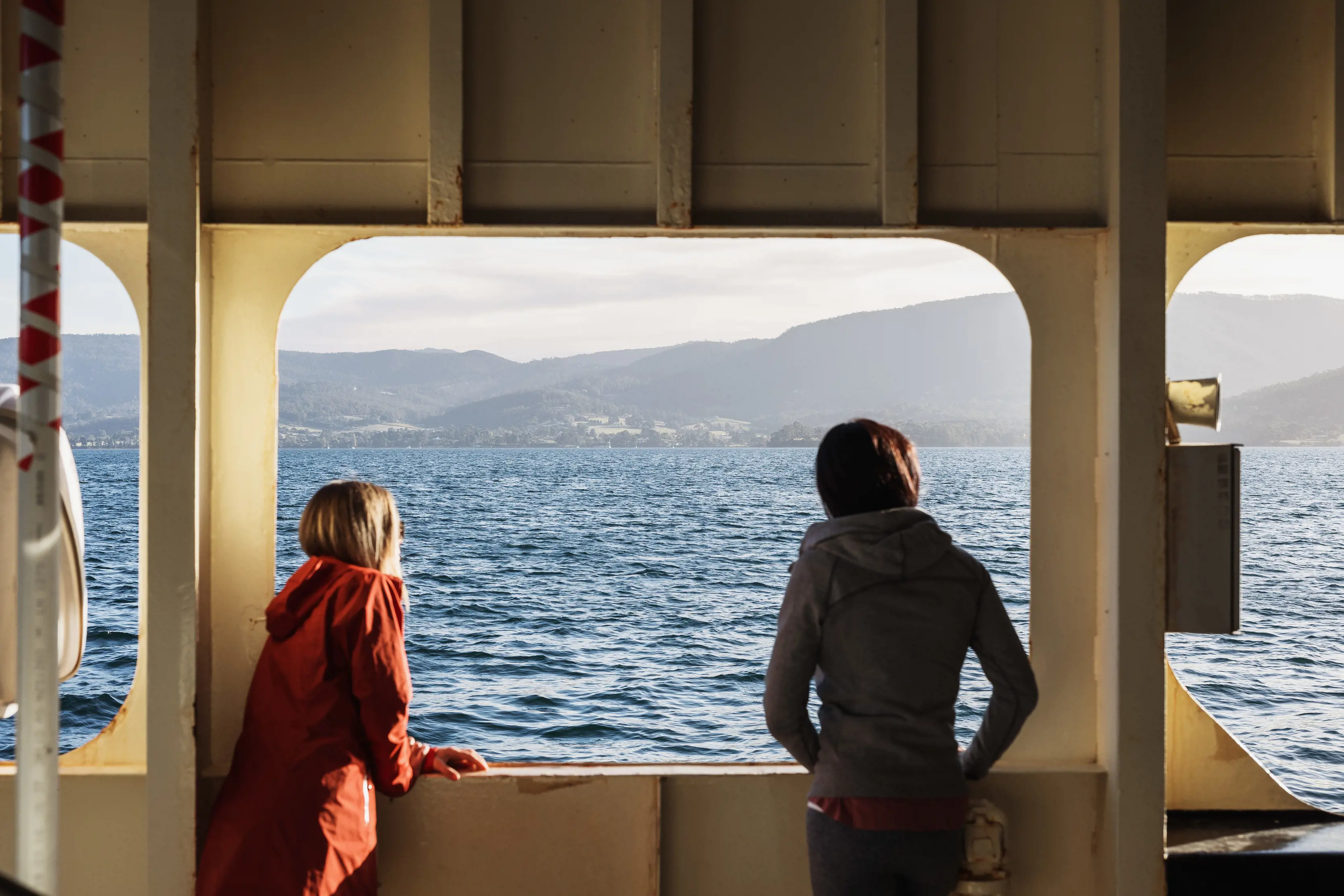 Two people look out over the waters of the D'Entrecasteaux Channel while riding The Bruny Island Ferry.