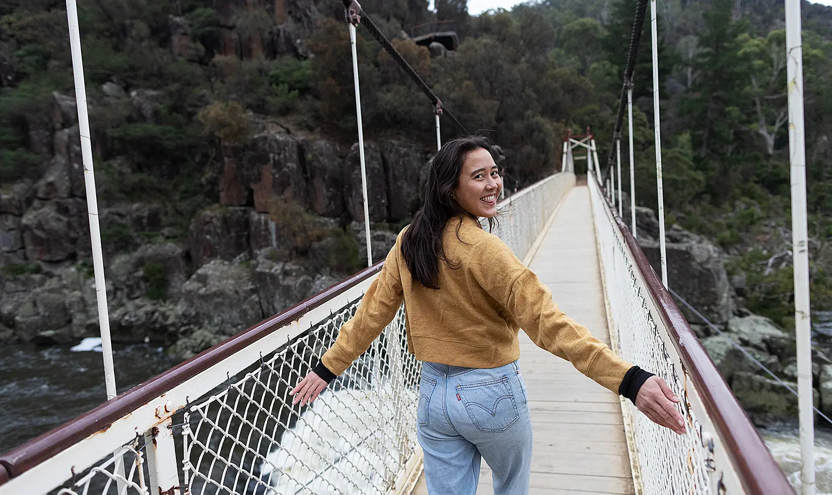 Woman walking across suspension bridge