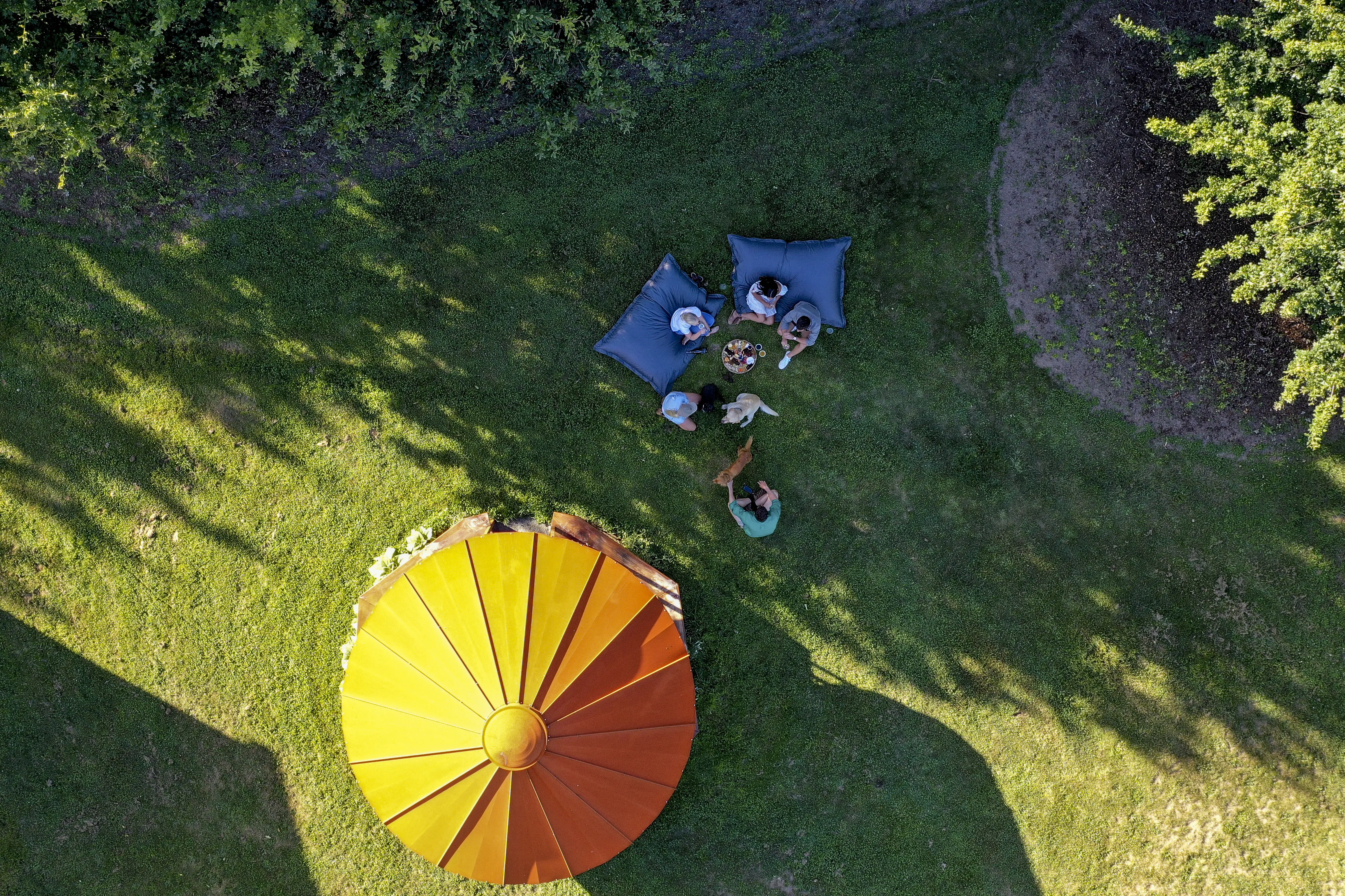 Picnic makers sitting under an umbrella in a farm