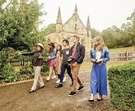 A small group walk through Port Arthur Historic Site with a tour guide.