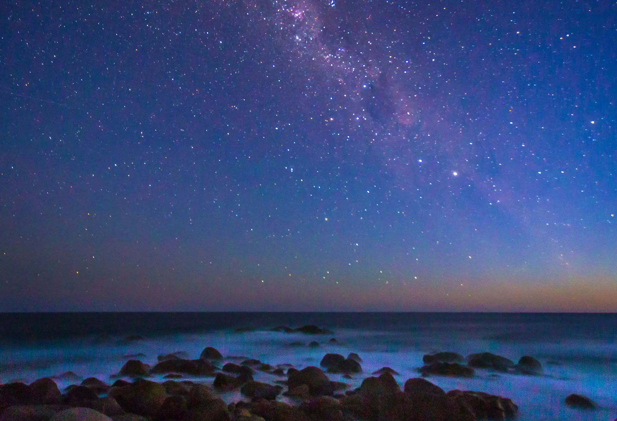 The sky is glowing colours from the Aurora Australis as seen from Freycinet National Park.