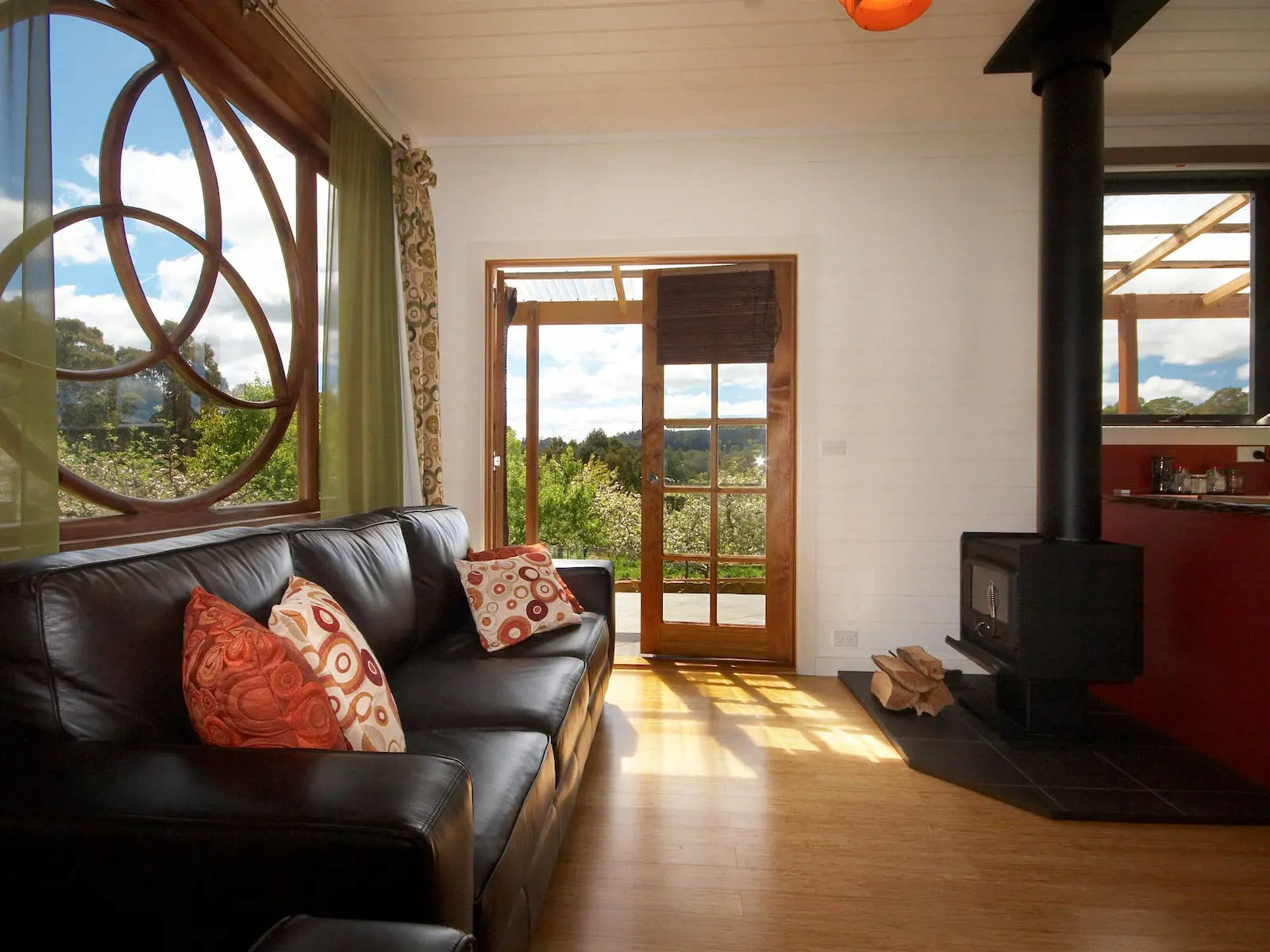 Interior of ElvenHome Cottage, with sunlight filtering through the windows and a door leading into a beautiful green garden.