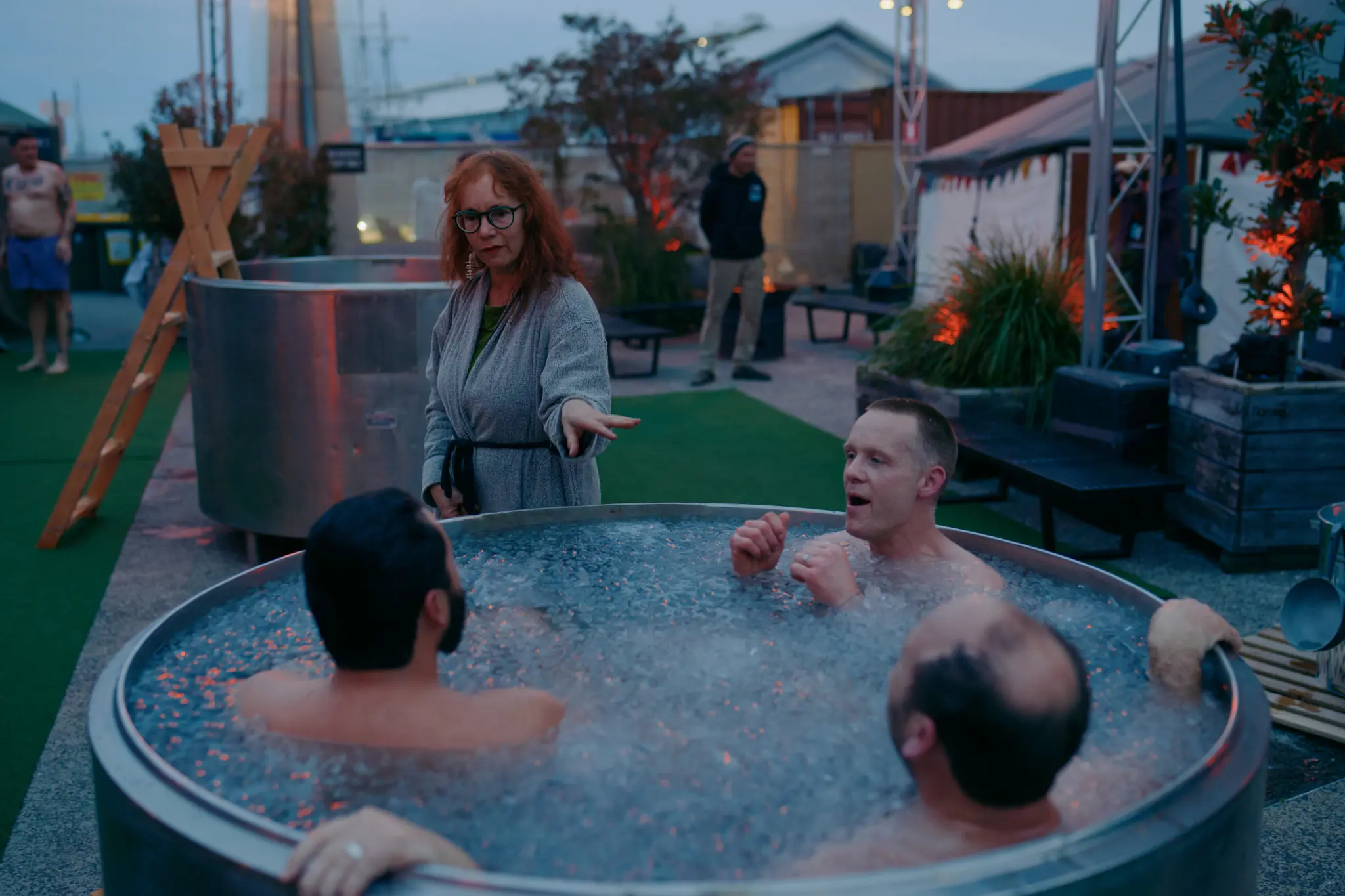 People soak in a metal stock tank full to the brim with icy cold water and icecubes.