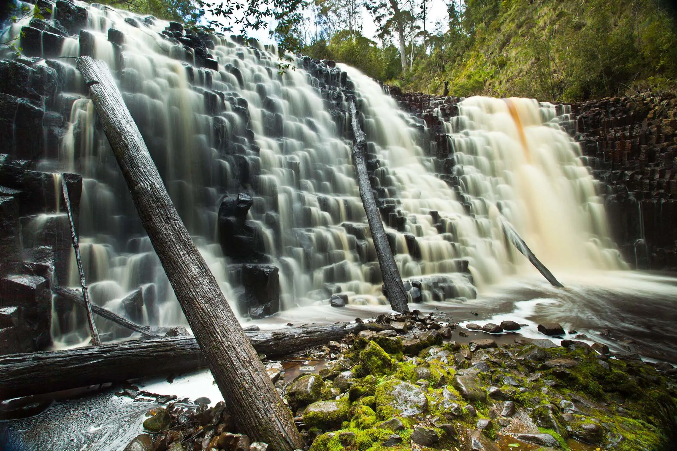 A waterfall cascades down a wide series of step-like stones, creating odd angles in the water.