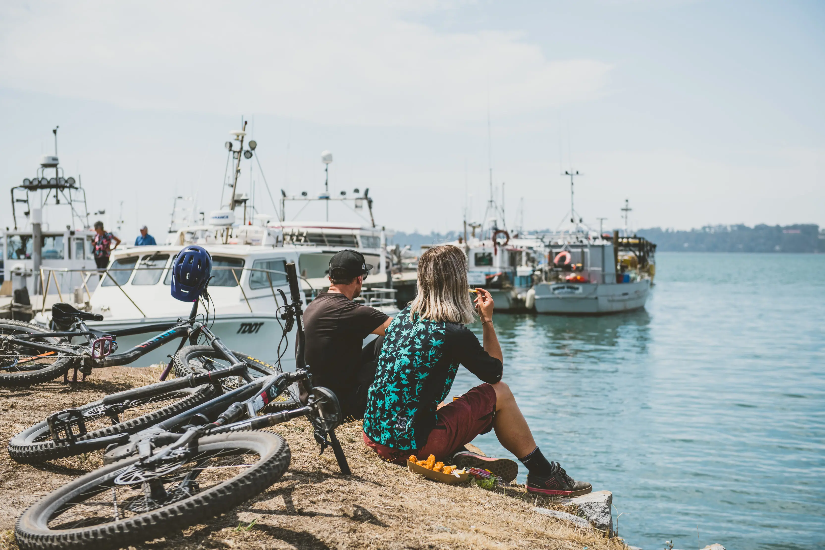 Couple eating fish and Chips by the Shore, St Helens, overlooking the clear, calm water.