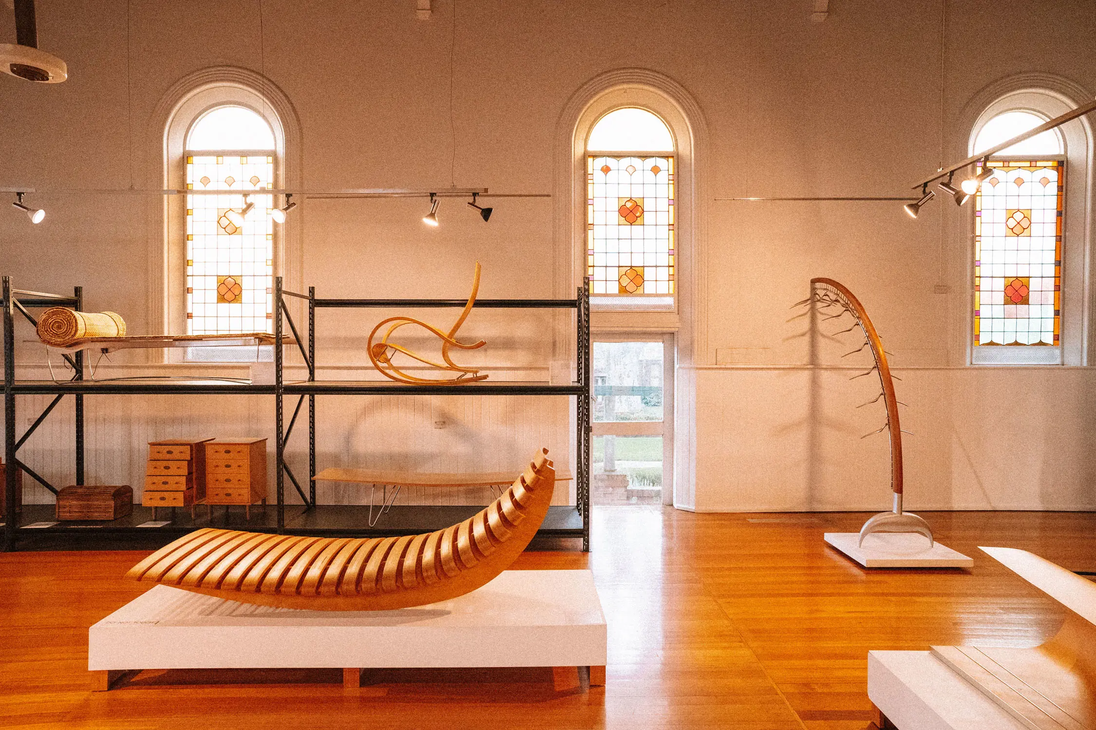 The interior of a furniture design studio, with many pieces of timber furniture displayed on shelves and pedestals.