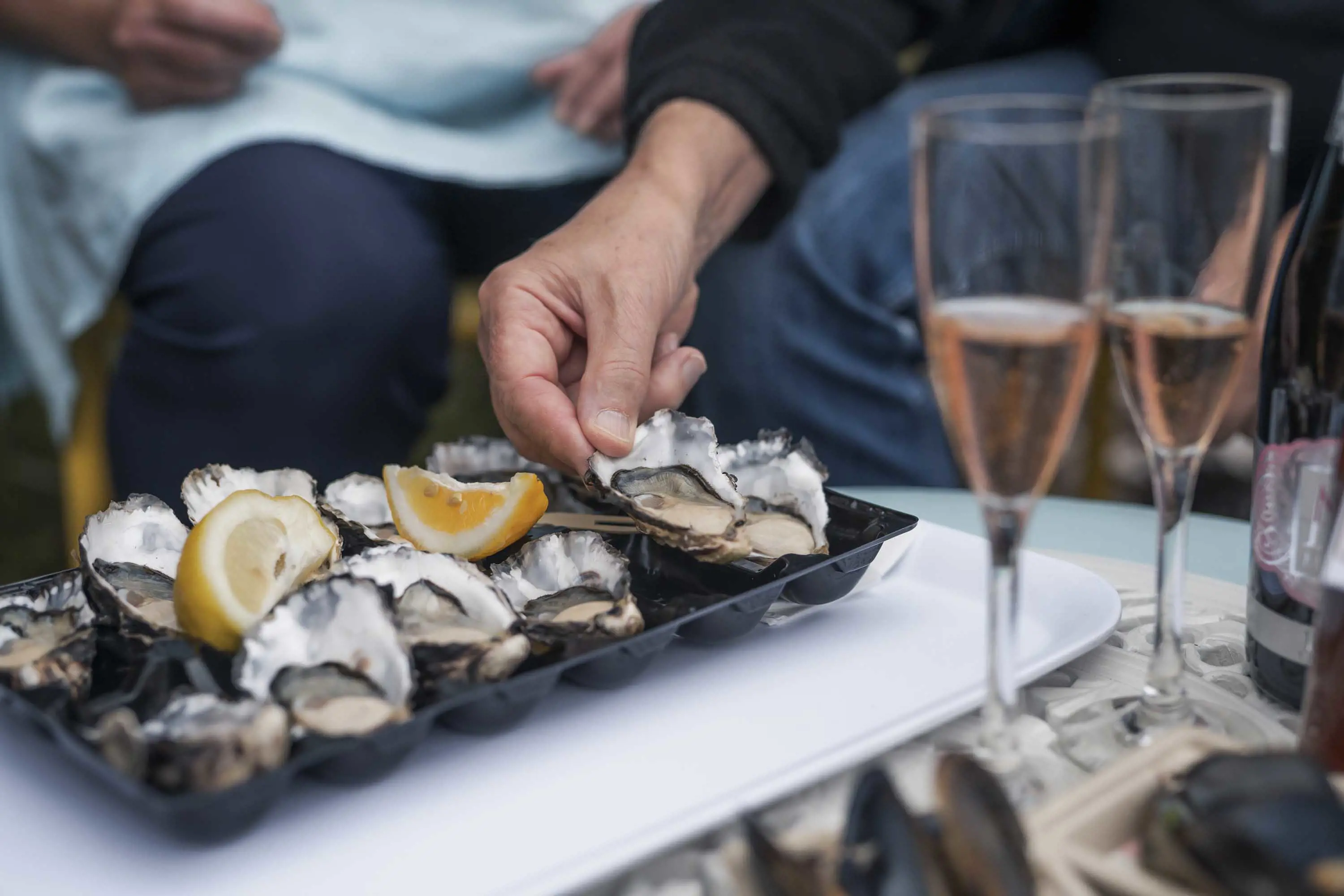 Fresh oysters presented in a tray and topped with freshly sliced lemons and salt.