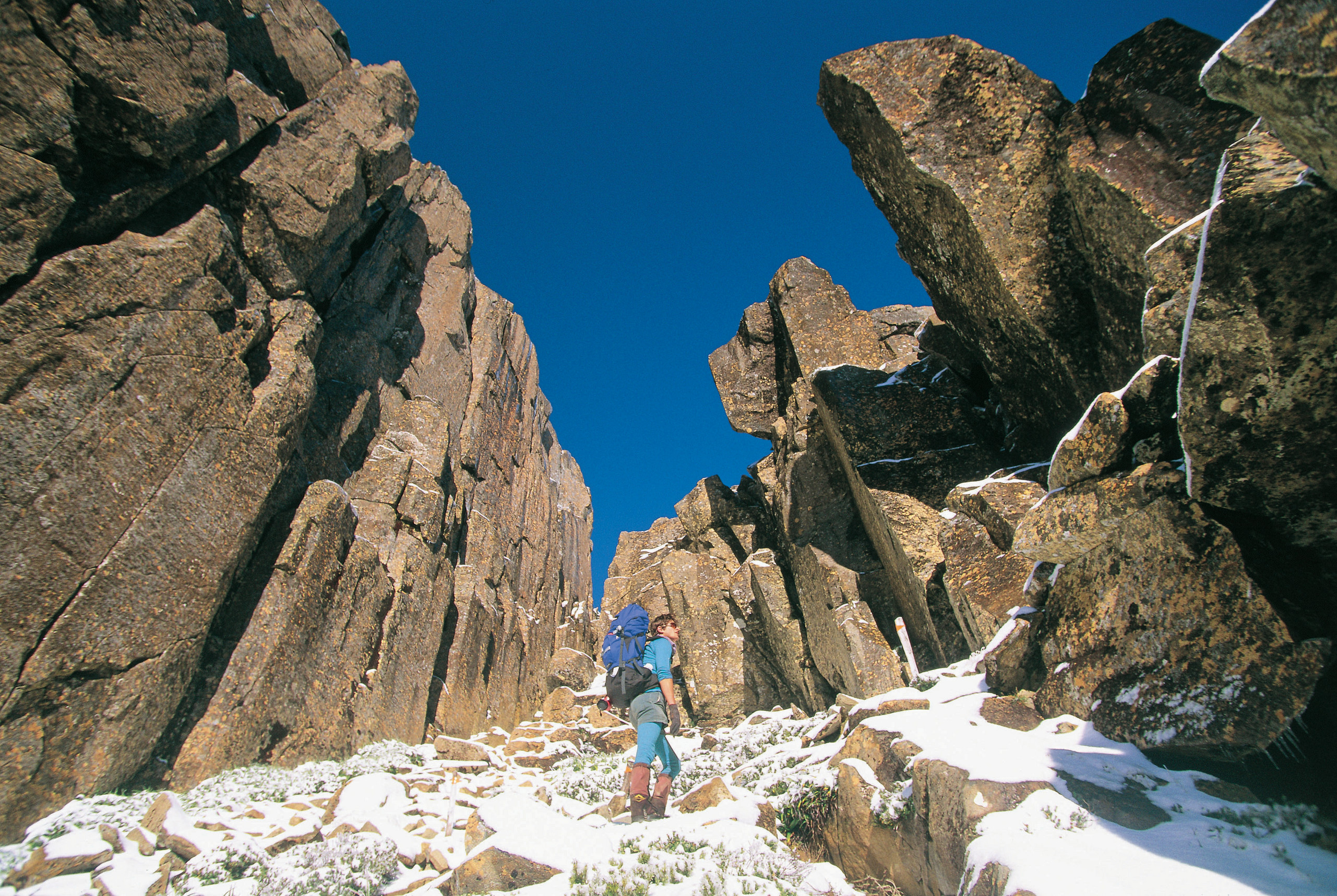 A hiker on the climb to Mt Ossa, Overland Track. The ground is covered in snow.