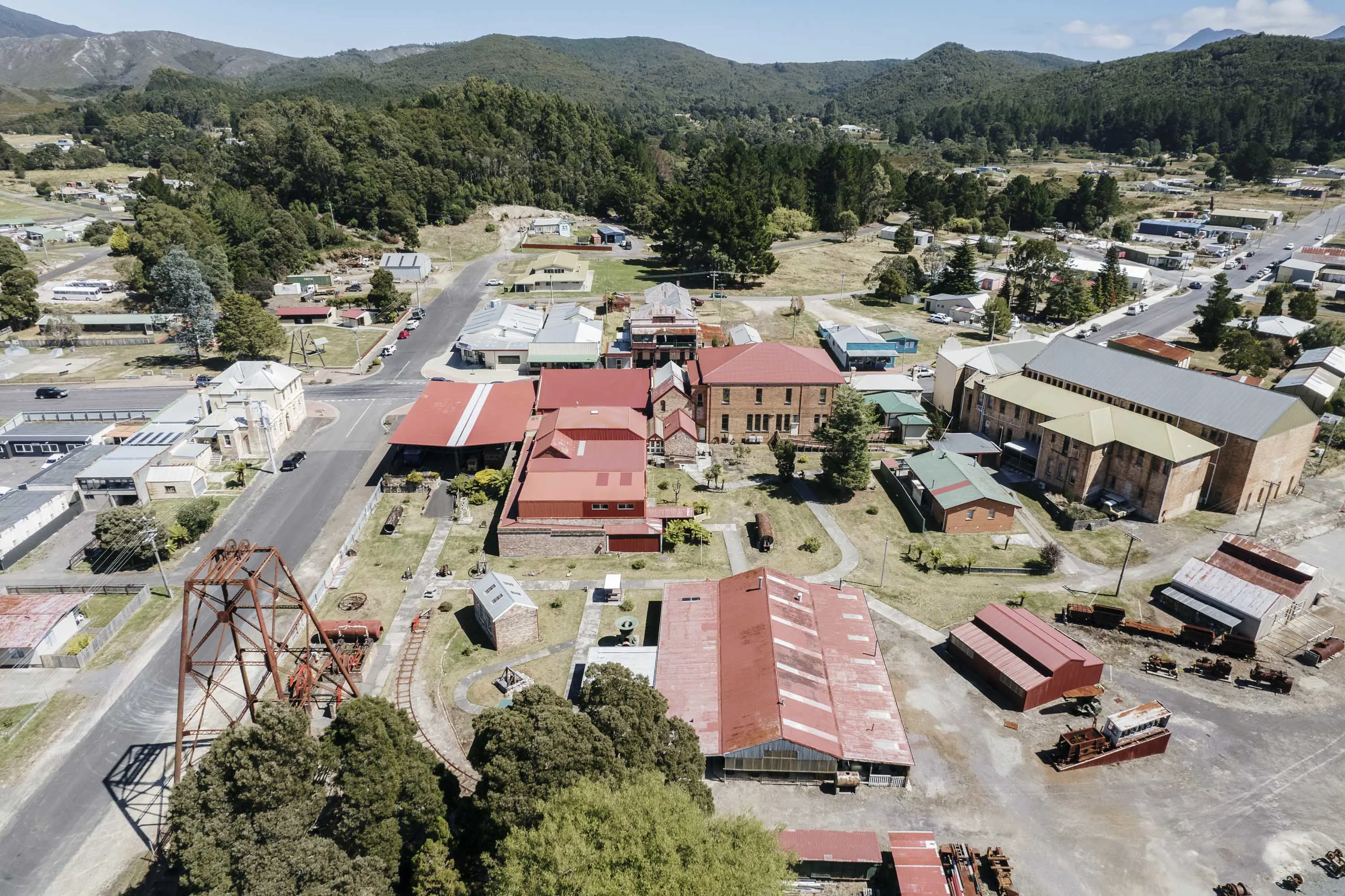 An aerial photograph of a mining town set amongst low lying mountains, with large red tin roof buildings of various shapes and sizes.