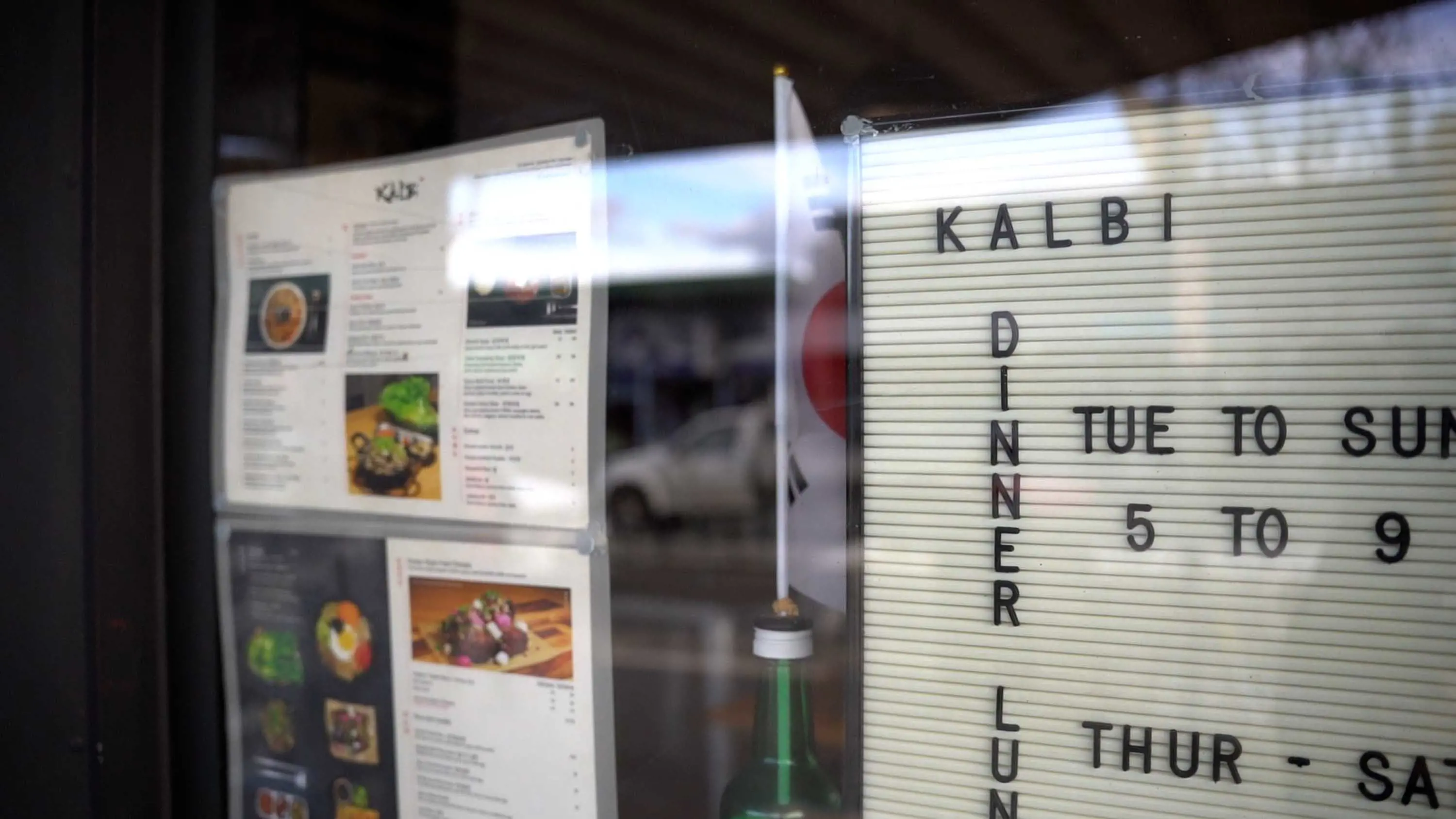 A menu is displayed ion the inside of a restaurant window.