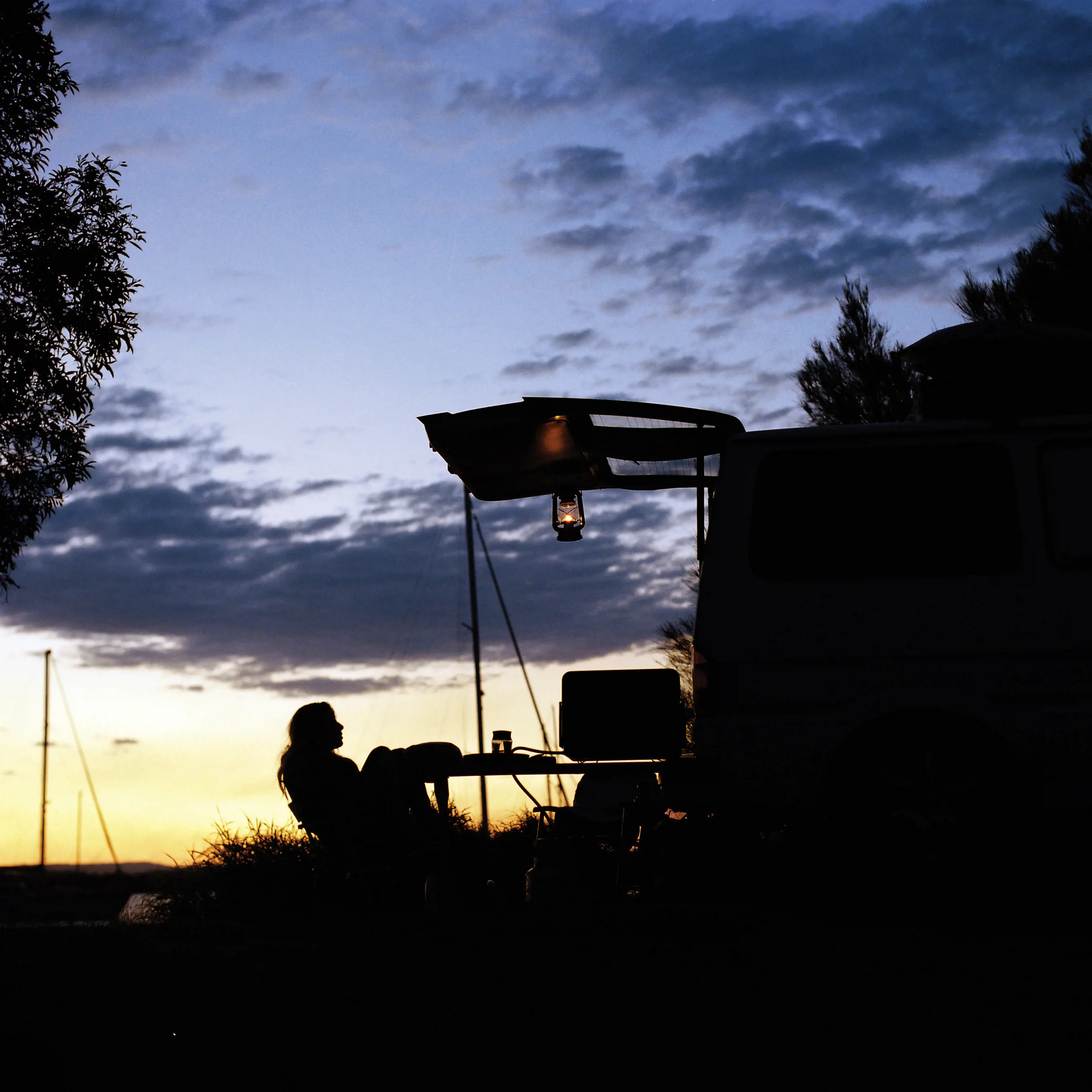 Silhouette of a person sat at a table at a campsite in West Tasmania.
