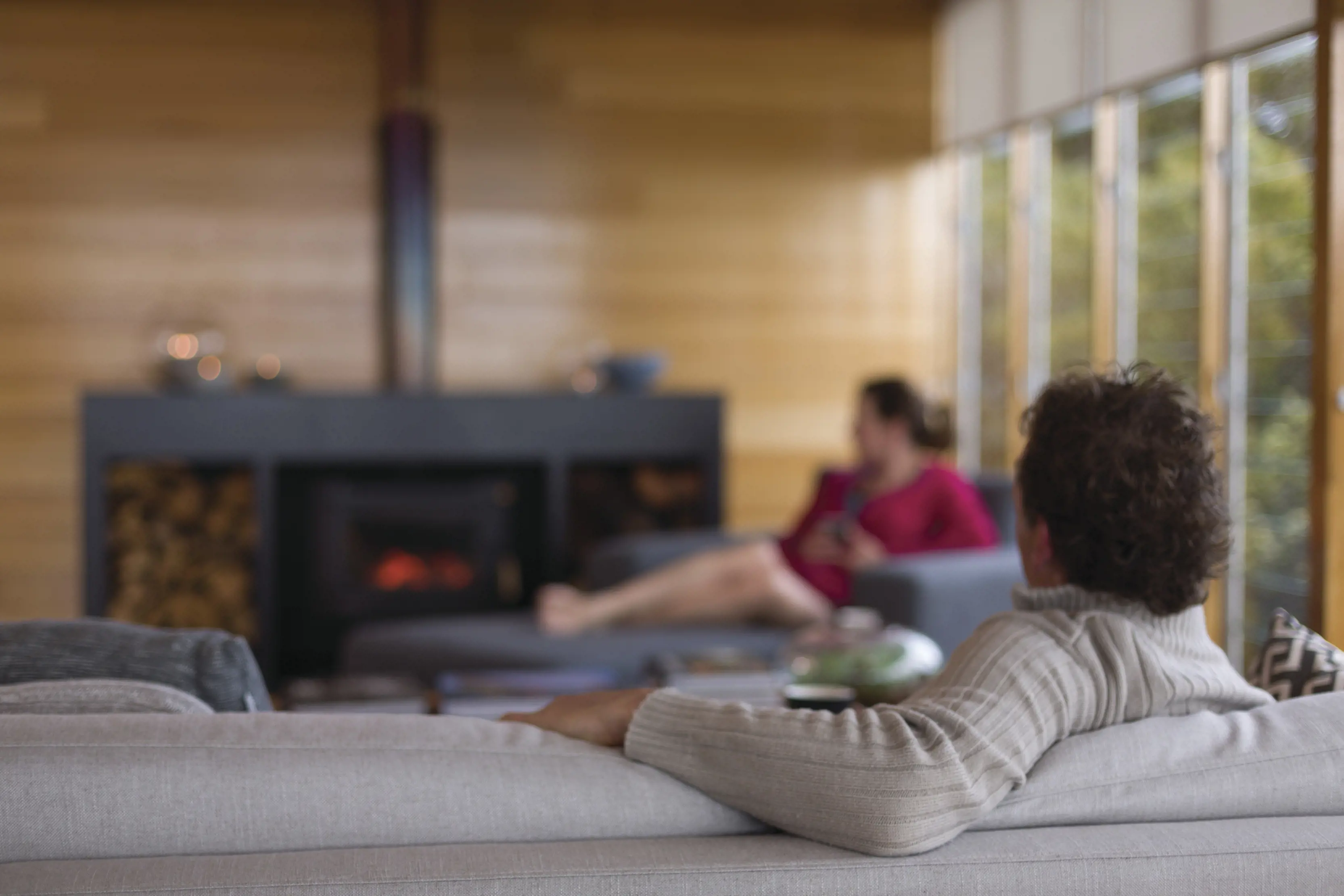 A couple sit inside by a log fire at Bay of Fires Lodge