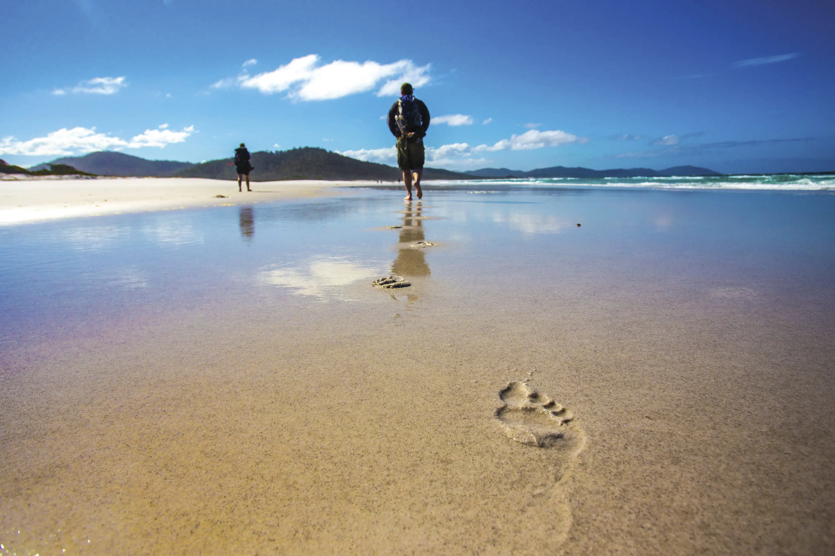 Footprints in the sand and people in the distance on The Freycinet Experience Walk