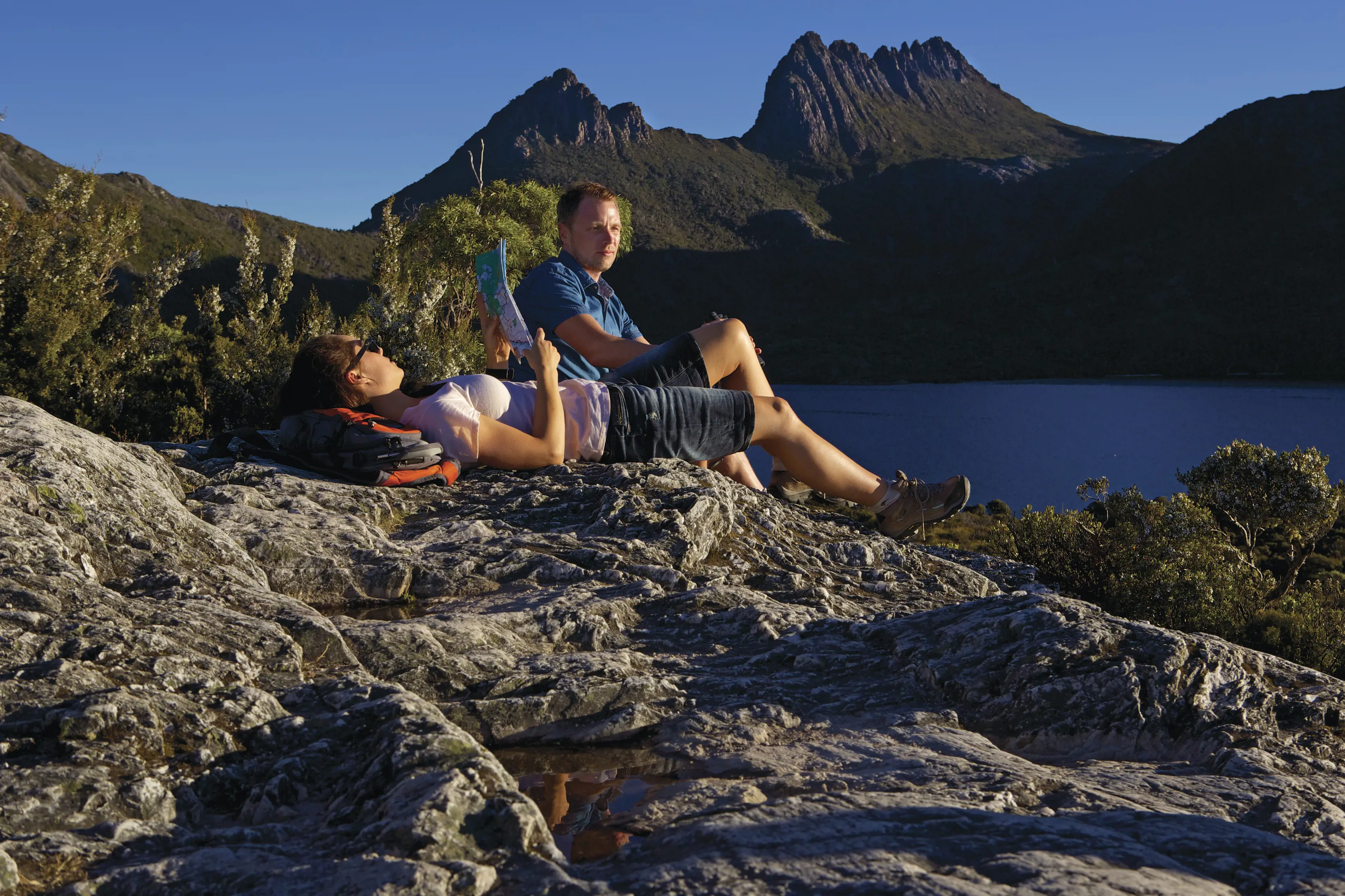 A couple rest and look at a map by Lake Dove, Cradle Mountain