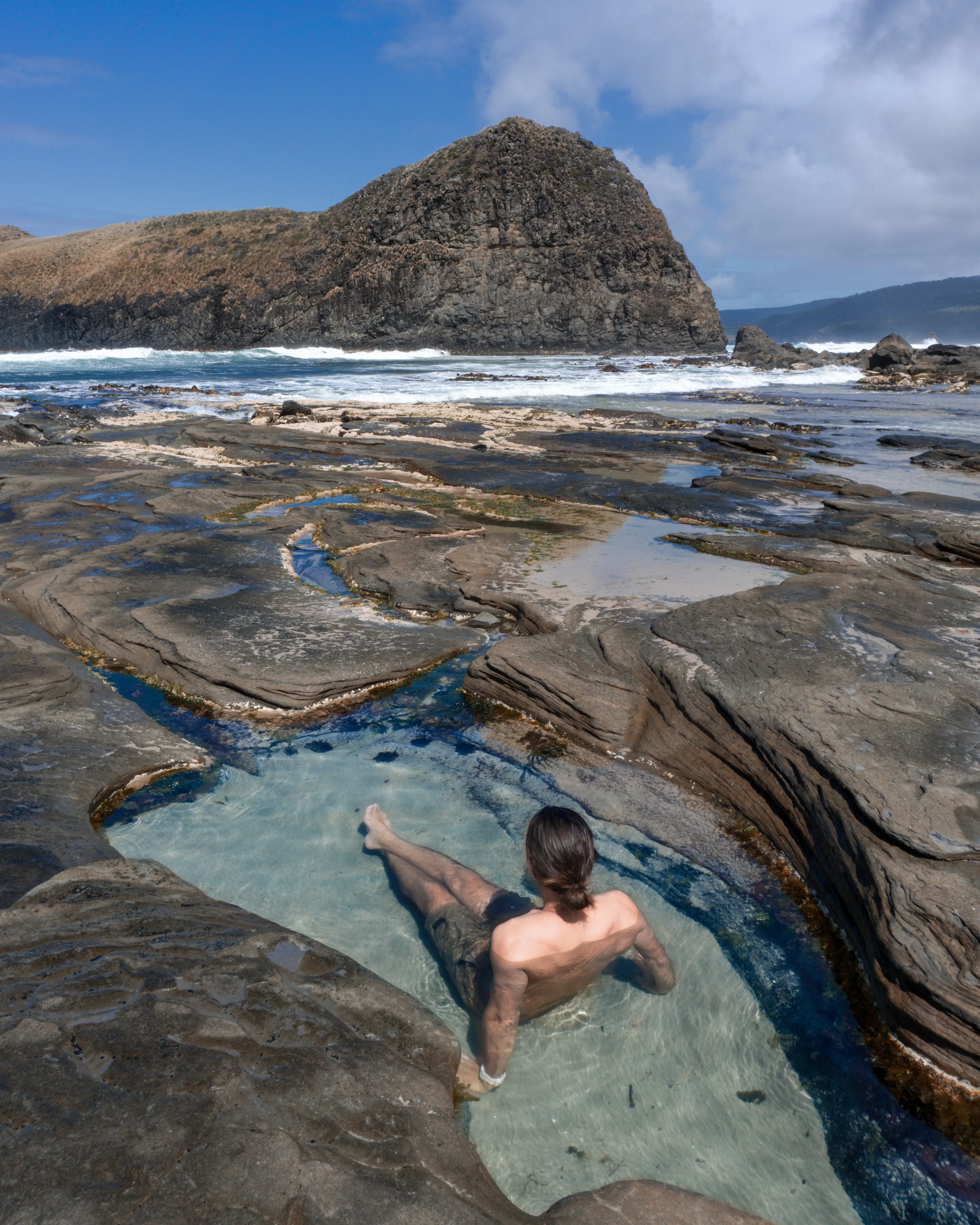 A man relaxes in a rock pool at South Cape Bay