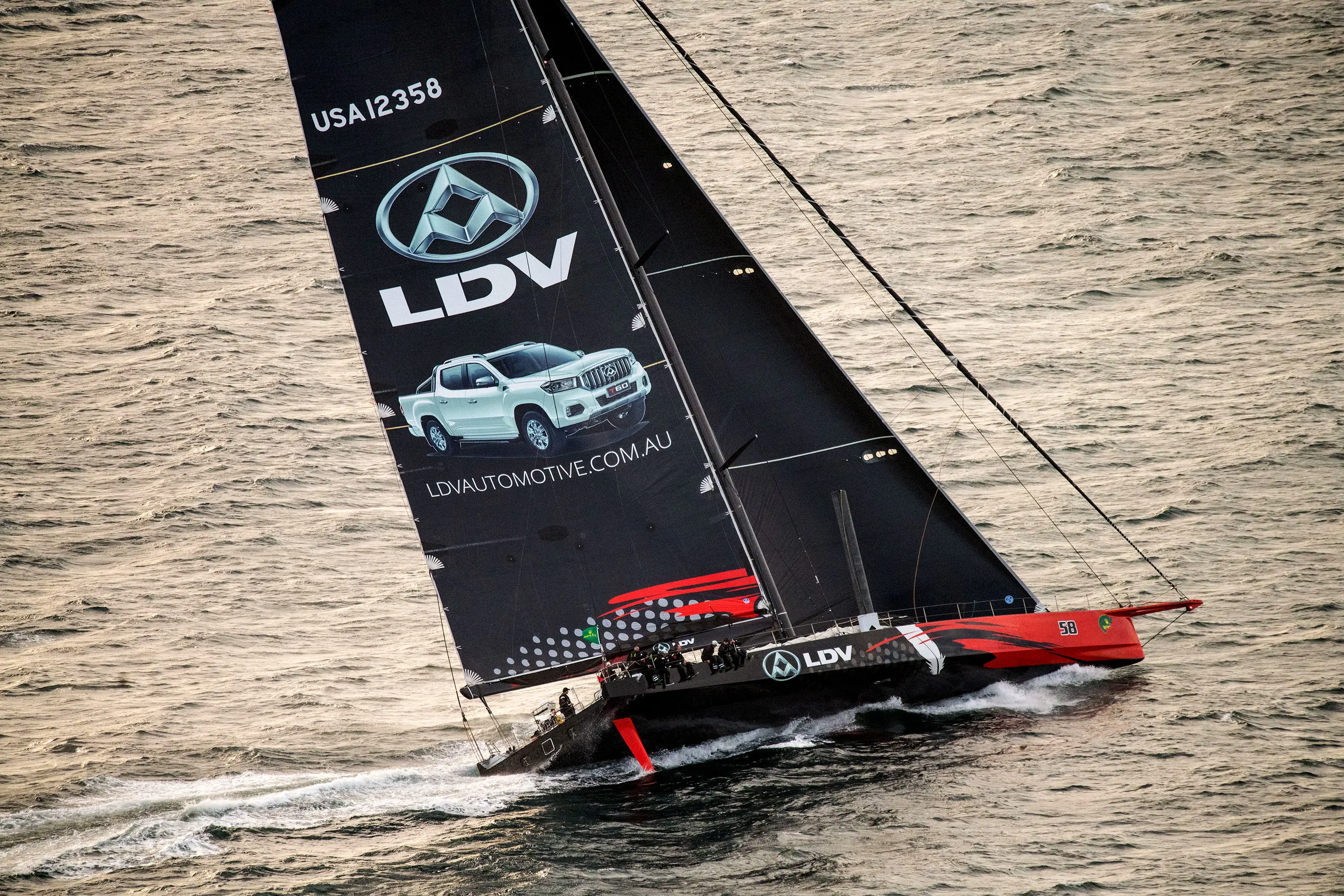 A large racing yacht leans into the waves to make a turn.
