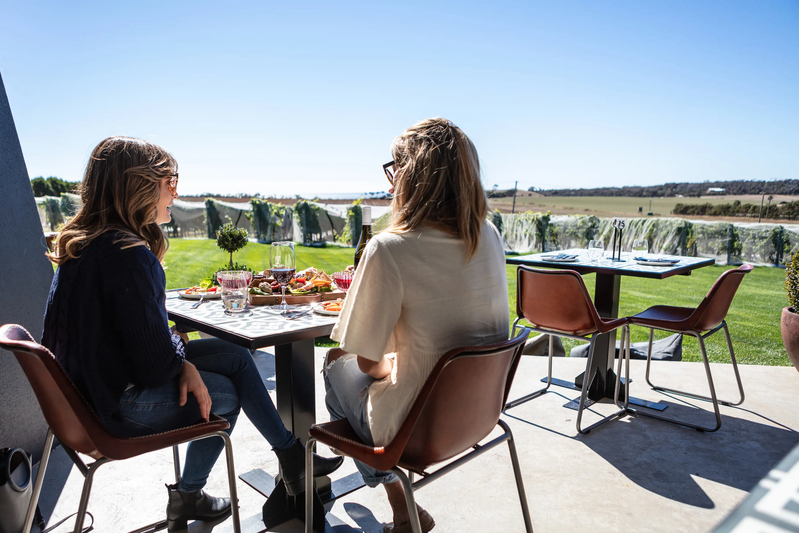 Two females enjoying food and wine by the vineyard at Ghost Rock Wines.