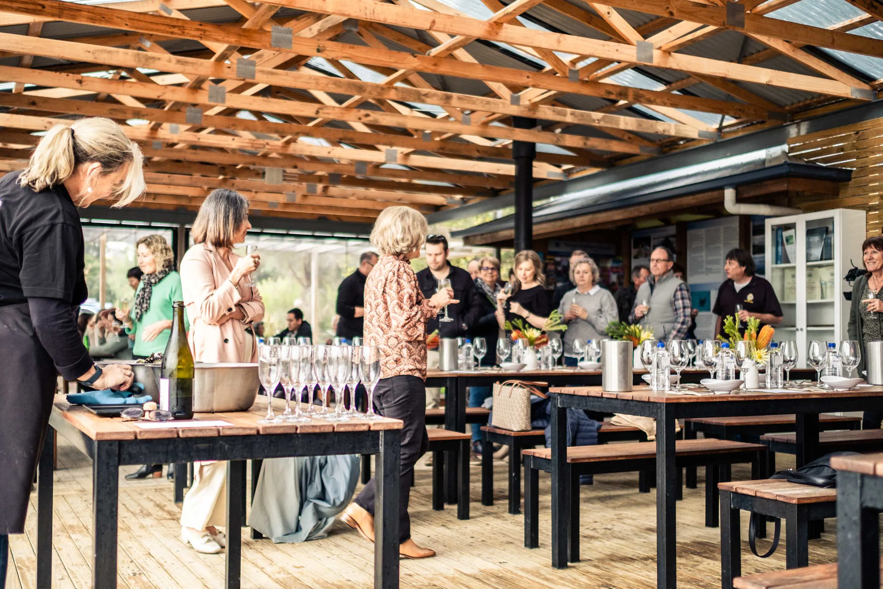 A group of people stand amongst wine tasting tables.