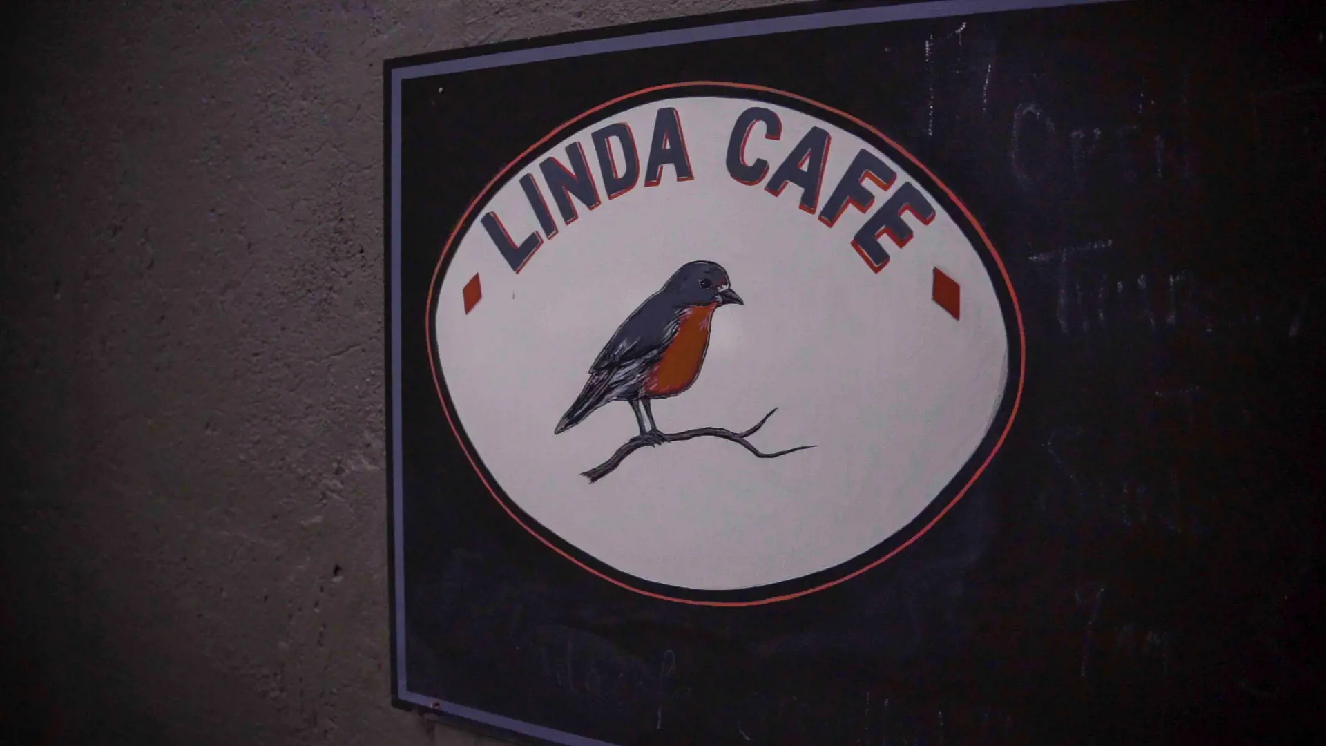 The Linda Cafe signage featuring a small red robin painted on a white oval background.