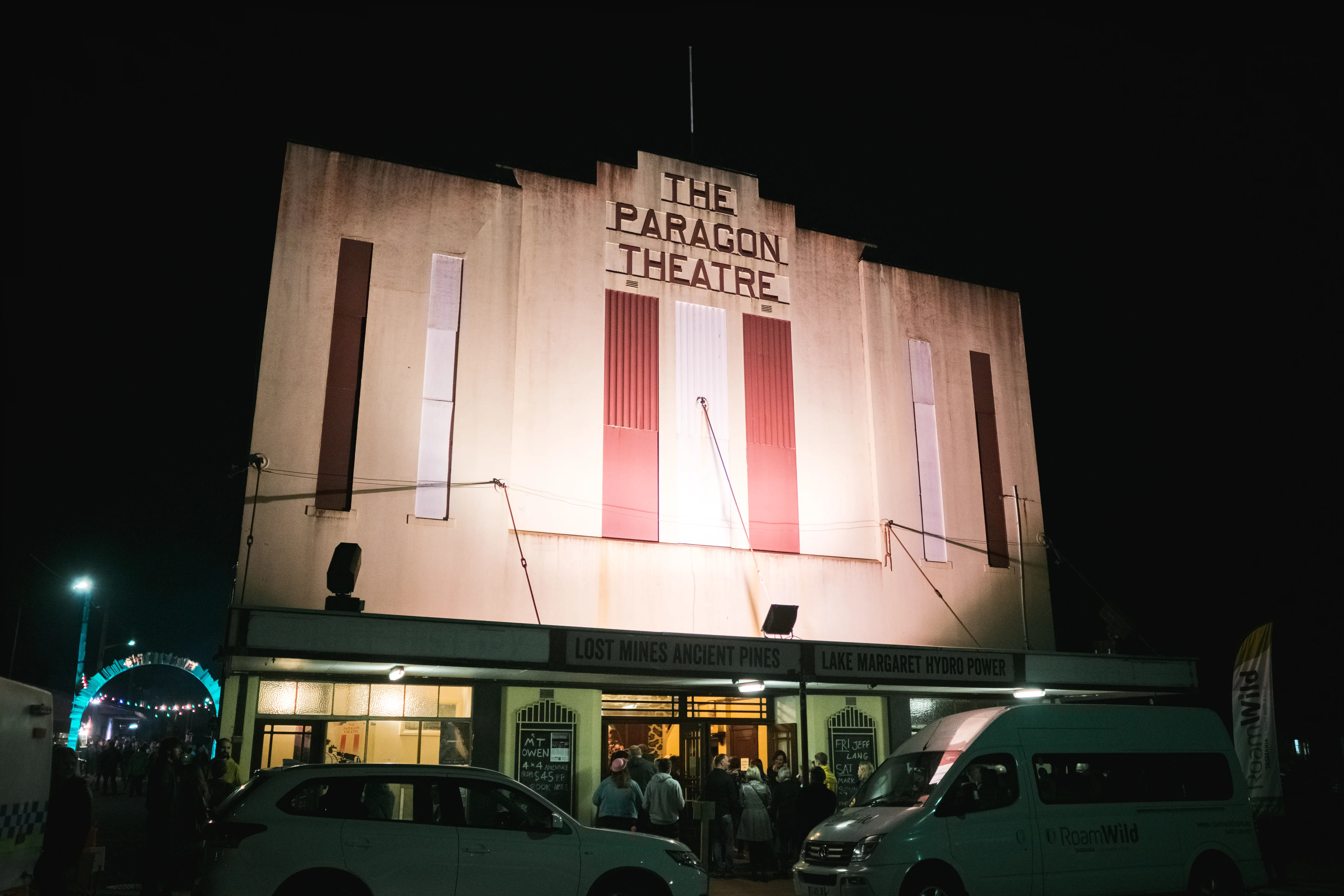 The tall, art-deco style facade of the Paragon Theatre is lit from below at night.