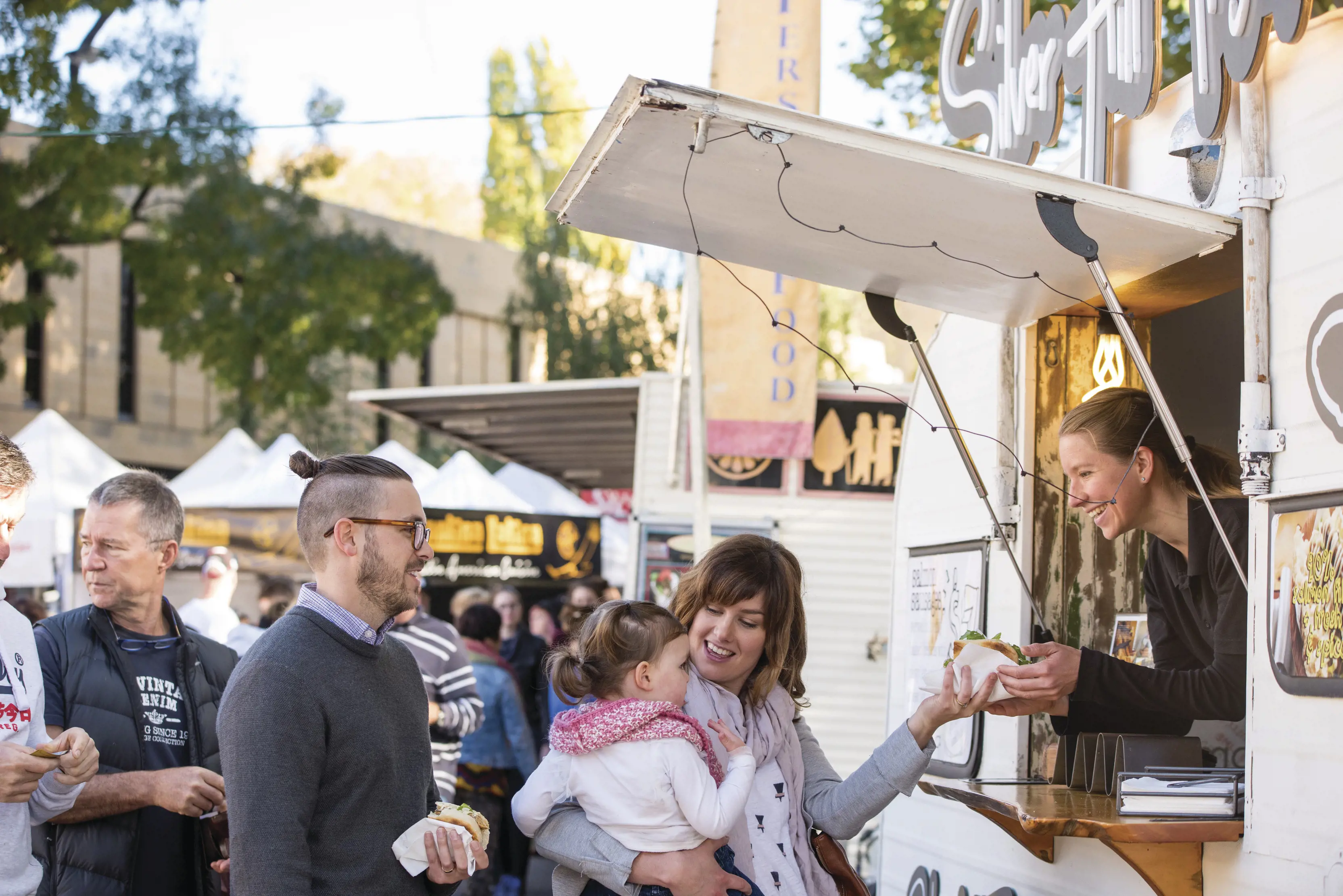 A family purchasing food at Salamanca Market. The market is set among the historic Georgian sandstone buildings of Salamanca Place in Hobart.