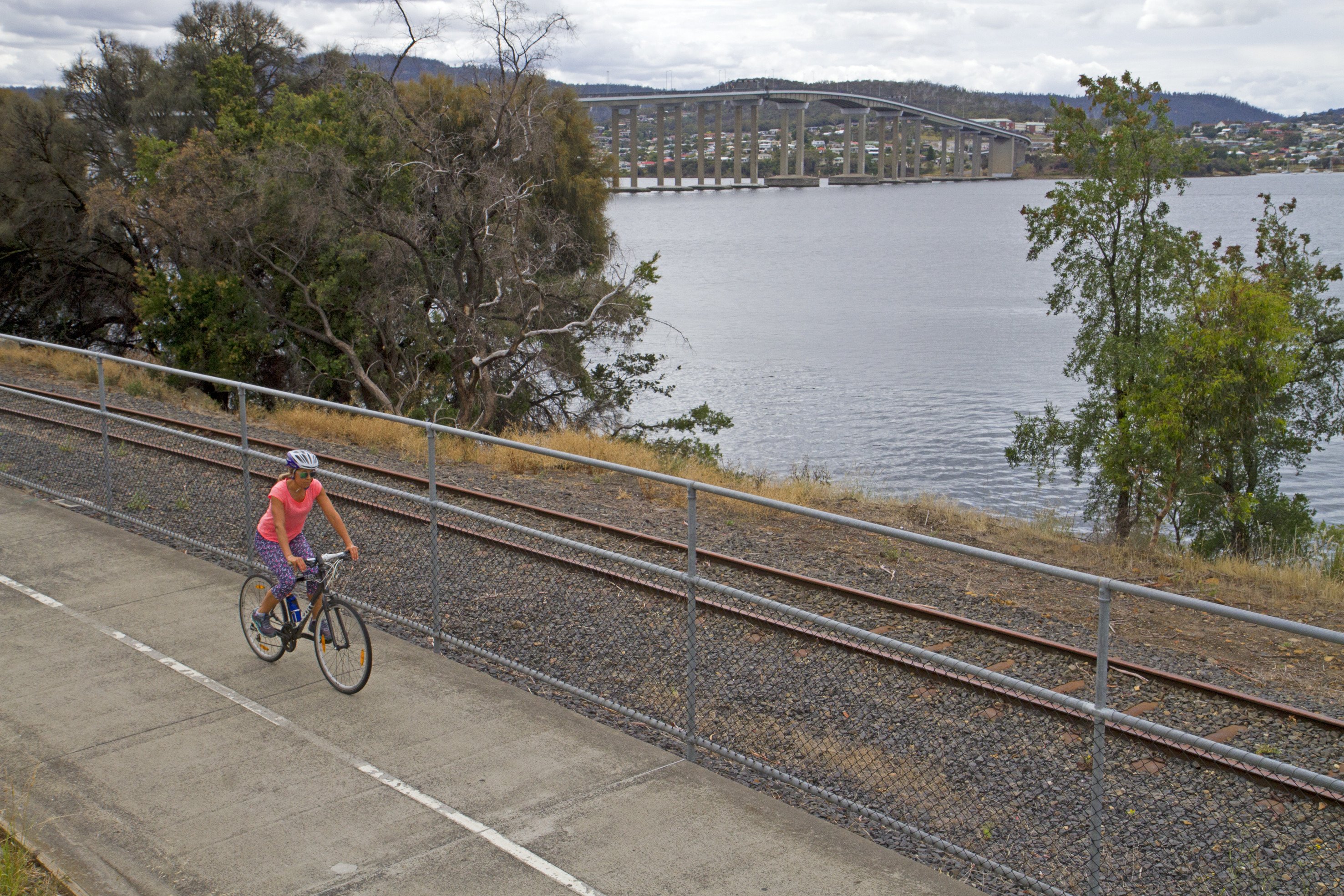 Female cyclist in an orange t-shirt on the Intercity Cycleway, Hobart to Glenorchy.