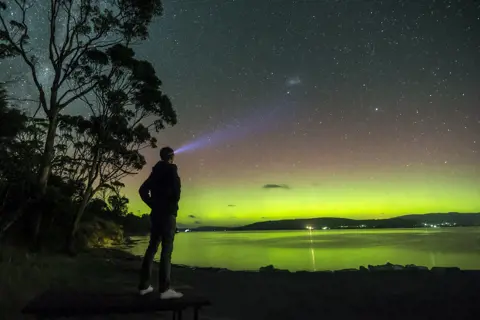 A man at night time looking at the Aurora Australis, Howden