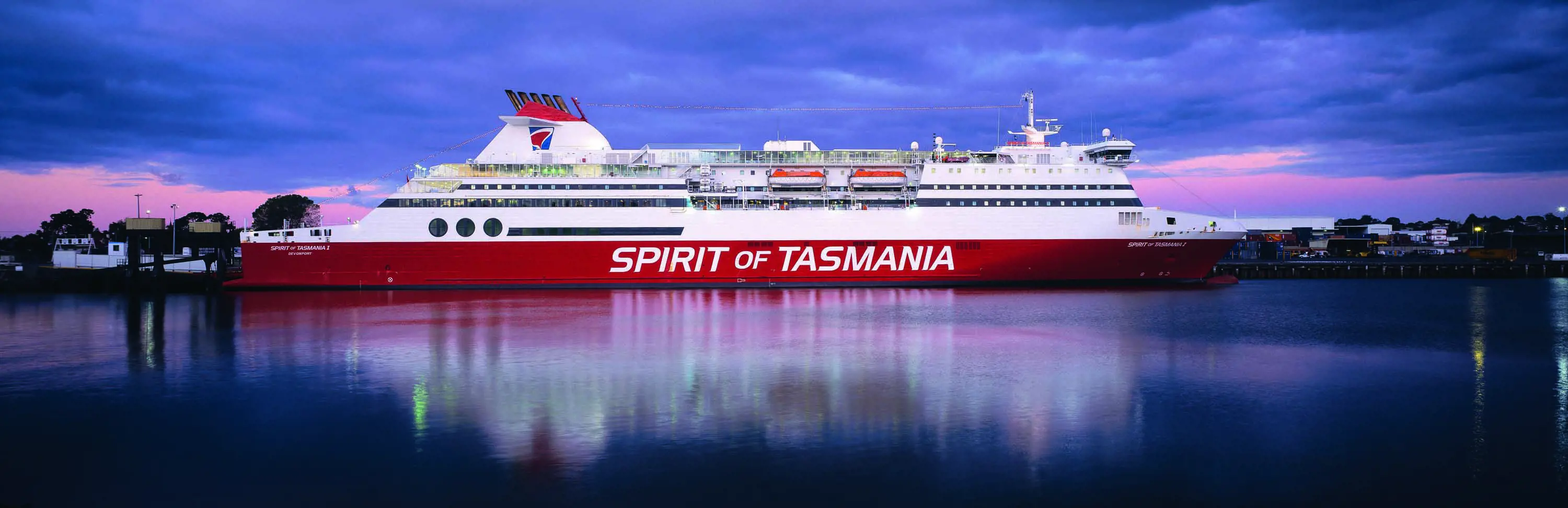 A long, red and white ferry with 3 stories, and white writing that reads Spirit of Tasmania along the side.
