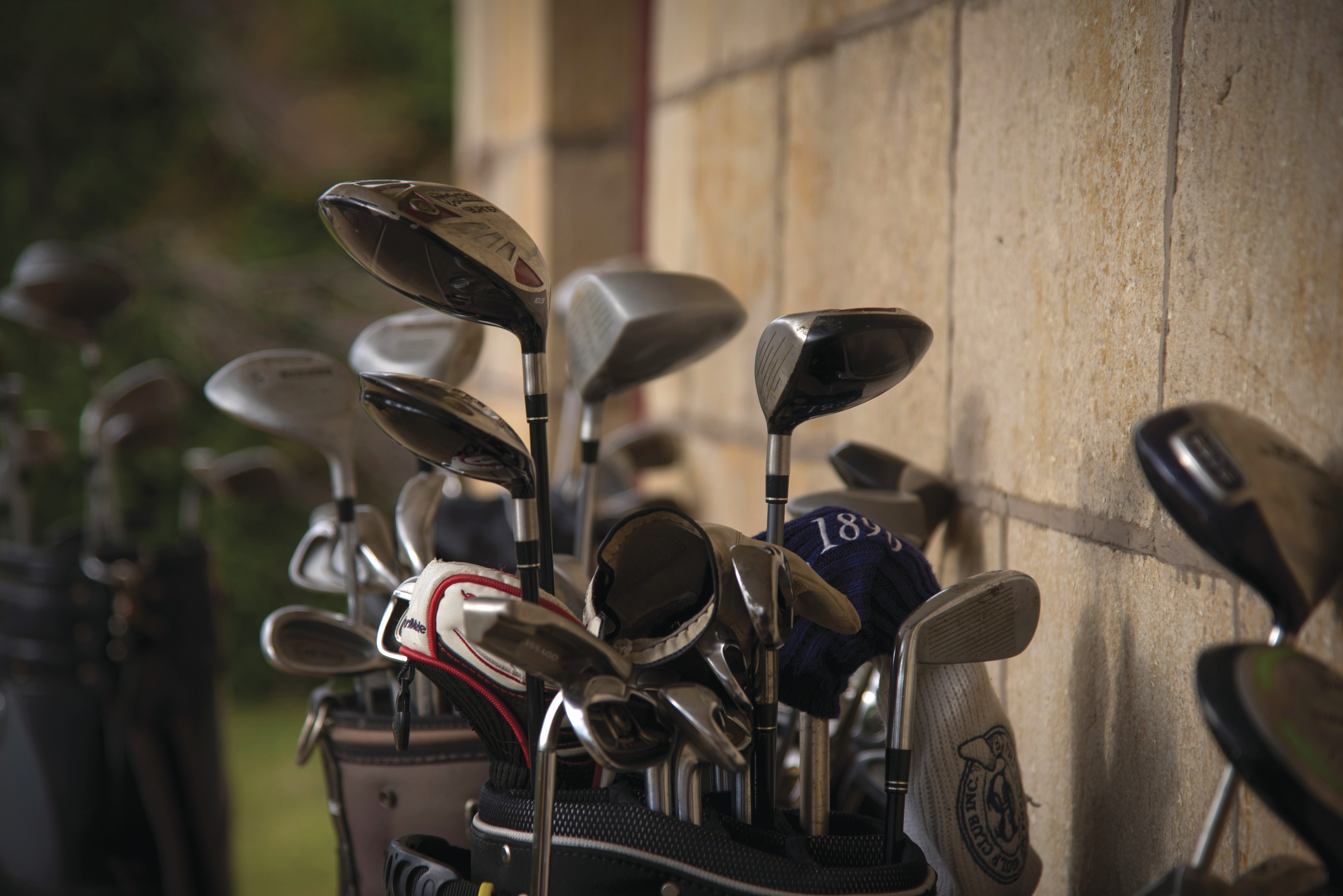 Close up of golf clubs against a brick wall at Ratho Farm golf course.