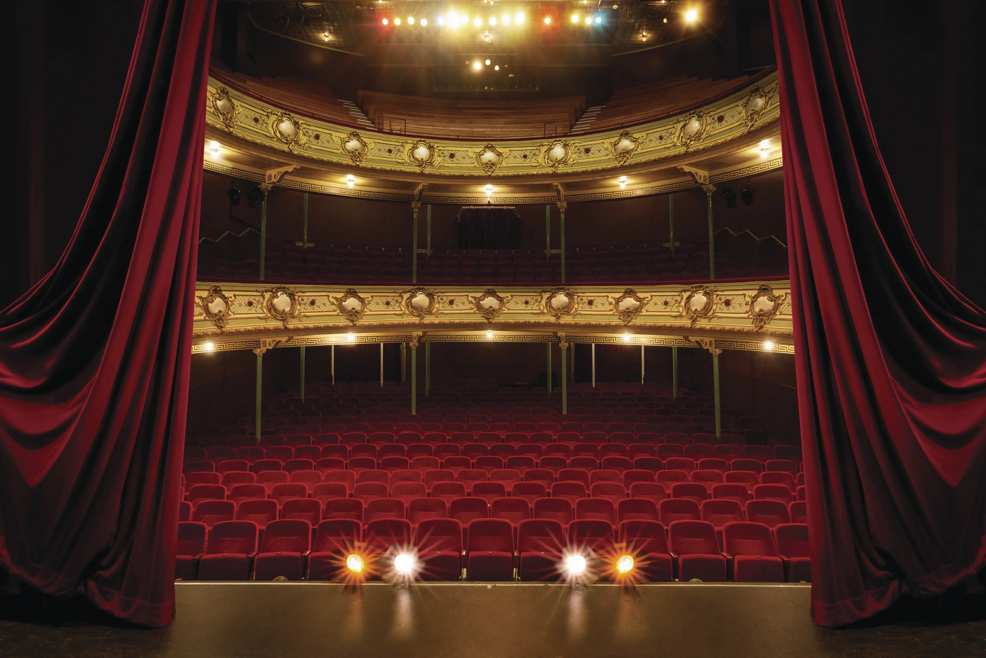 Interior image from the point of view of the stage, looking out at the empty red seats at Theatre Royal.