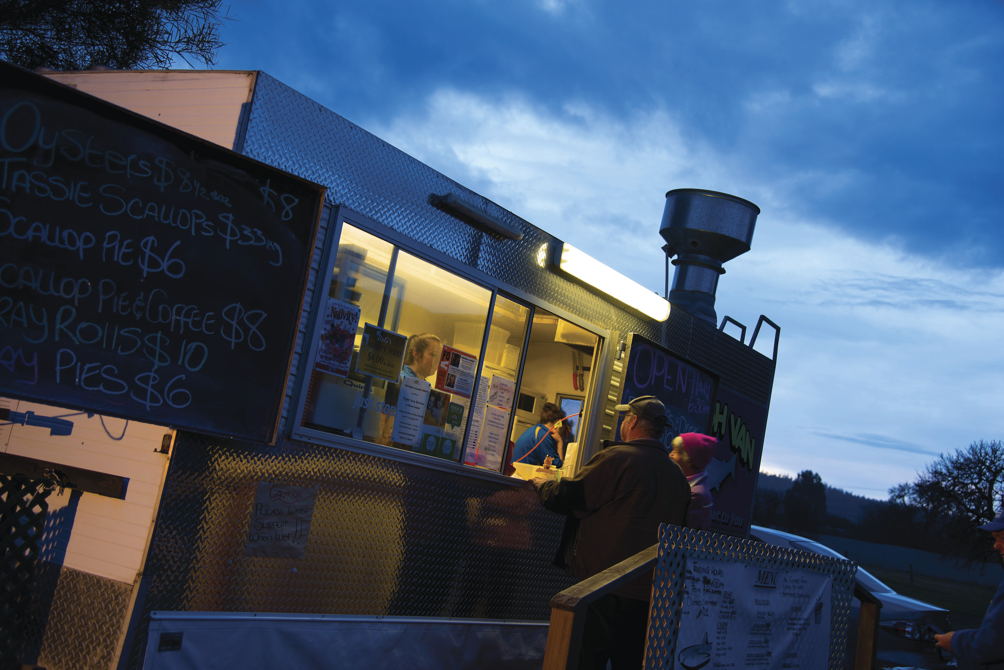 "Image of a couple ordering food on dusk at The Fish Van, Triabunna. "