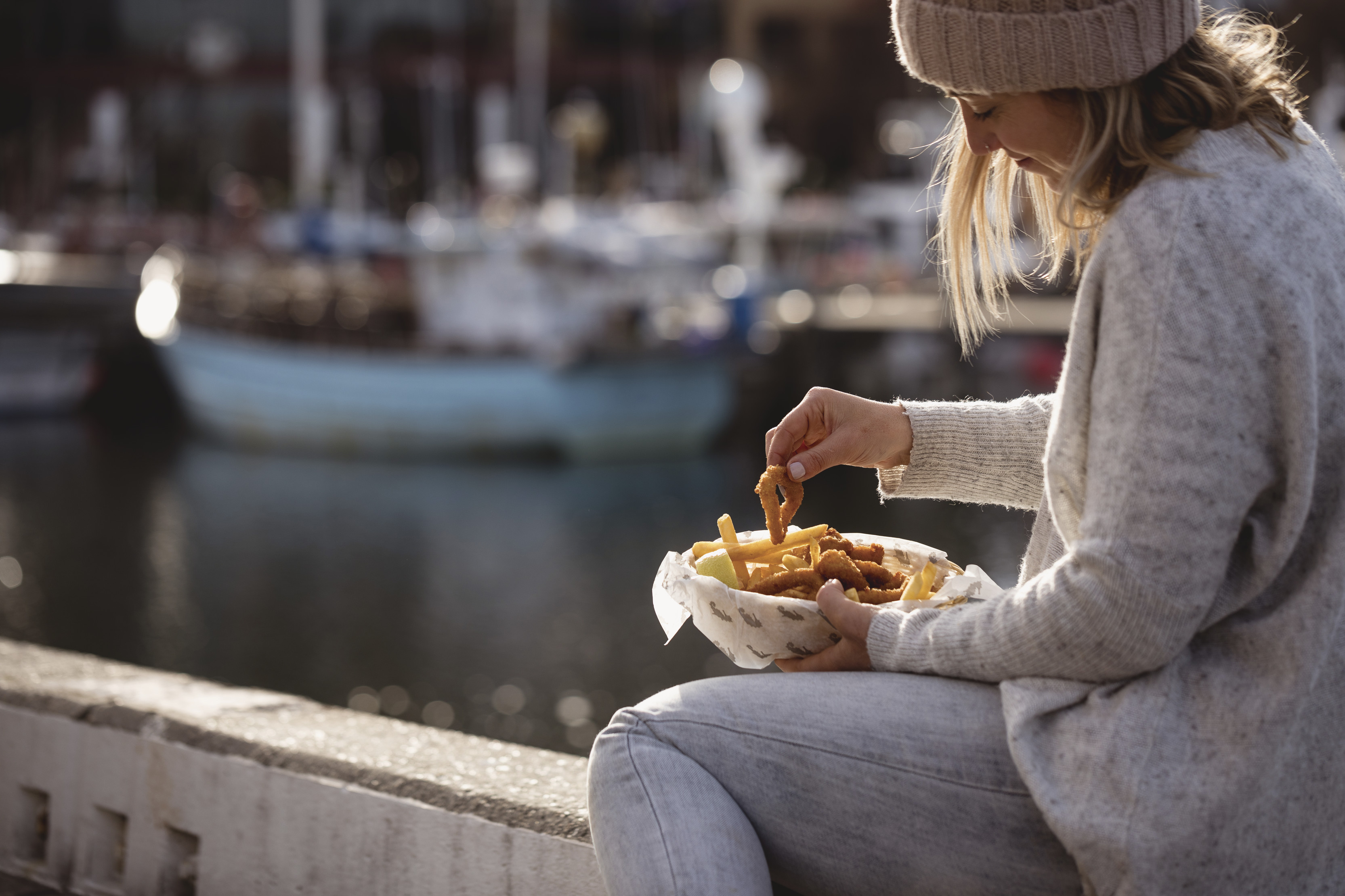 Person eating chips by the water at Seafood on Hobart Waterfront.