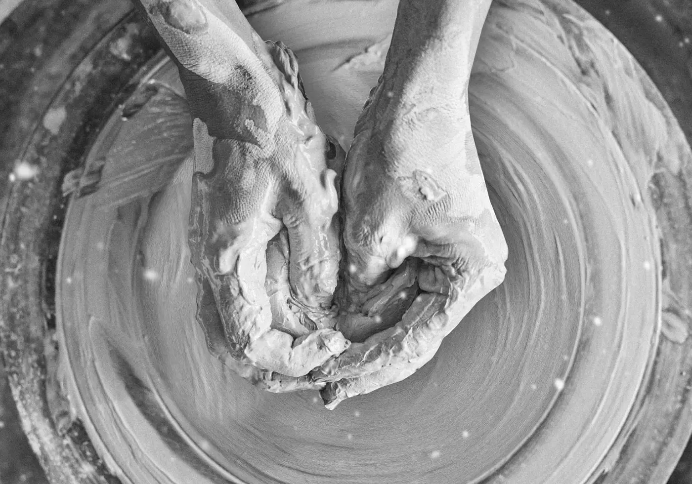 Two hands shaping wet clay on a pottery wheel.