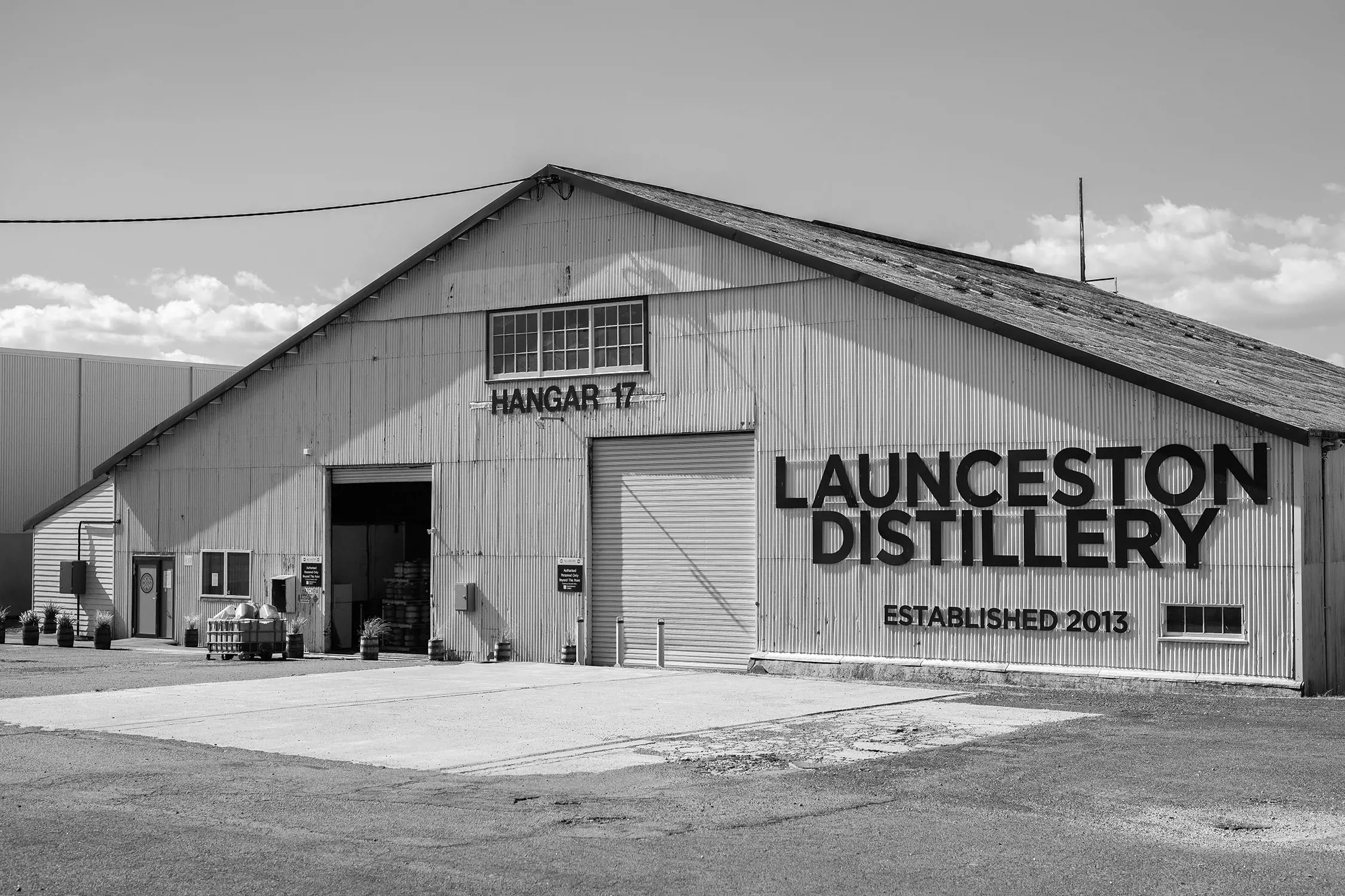 The outside of a large corrugated iron warehouse-style building. Black lettering on it reads 'Hangar 17' and 'Launceston Distillery established 2013'. 