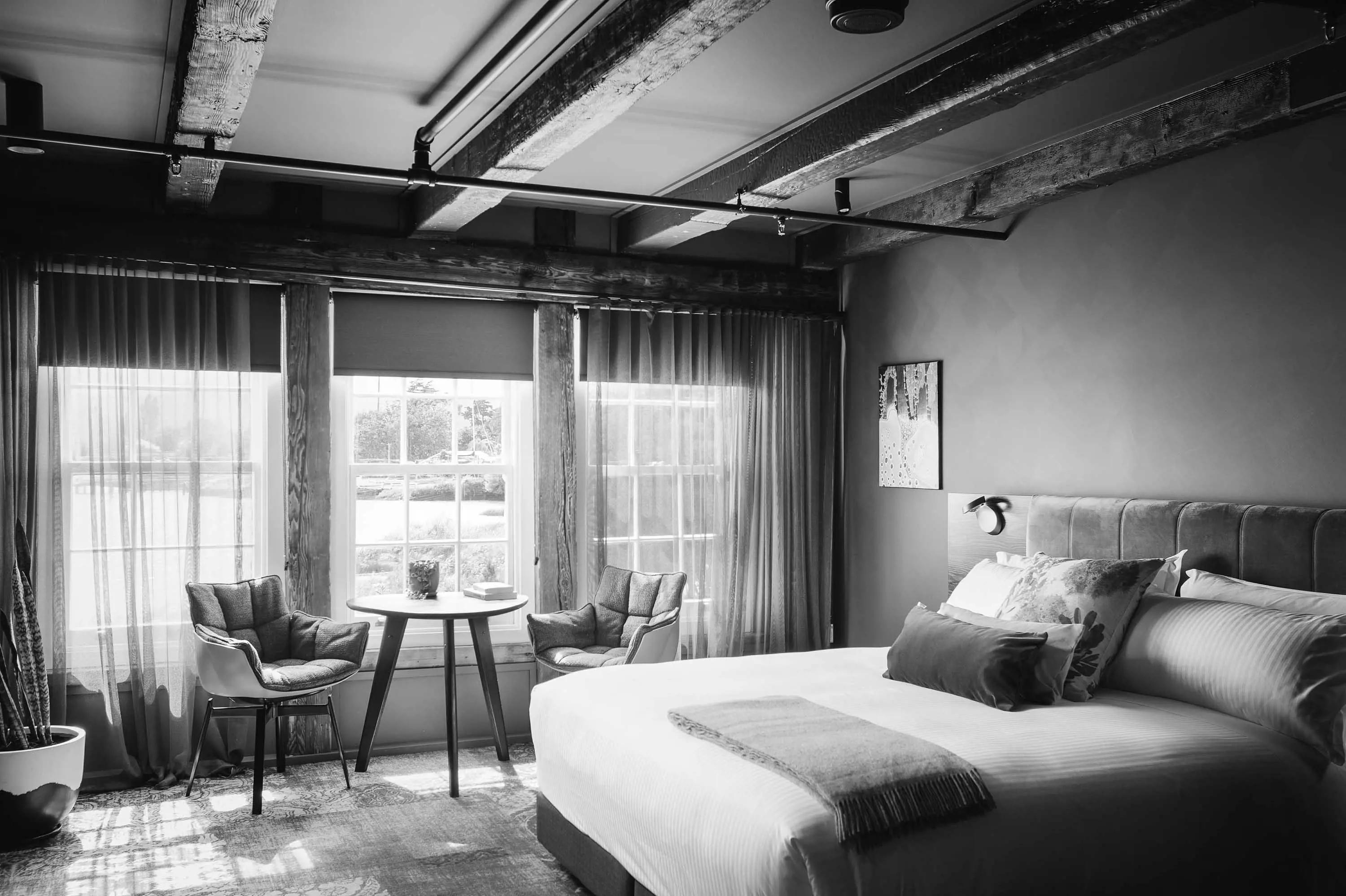 A bright and airy hotel room with large windows and contemporary furniture.