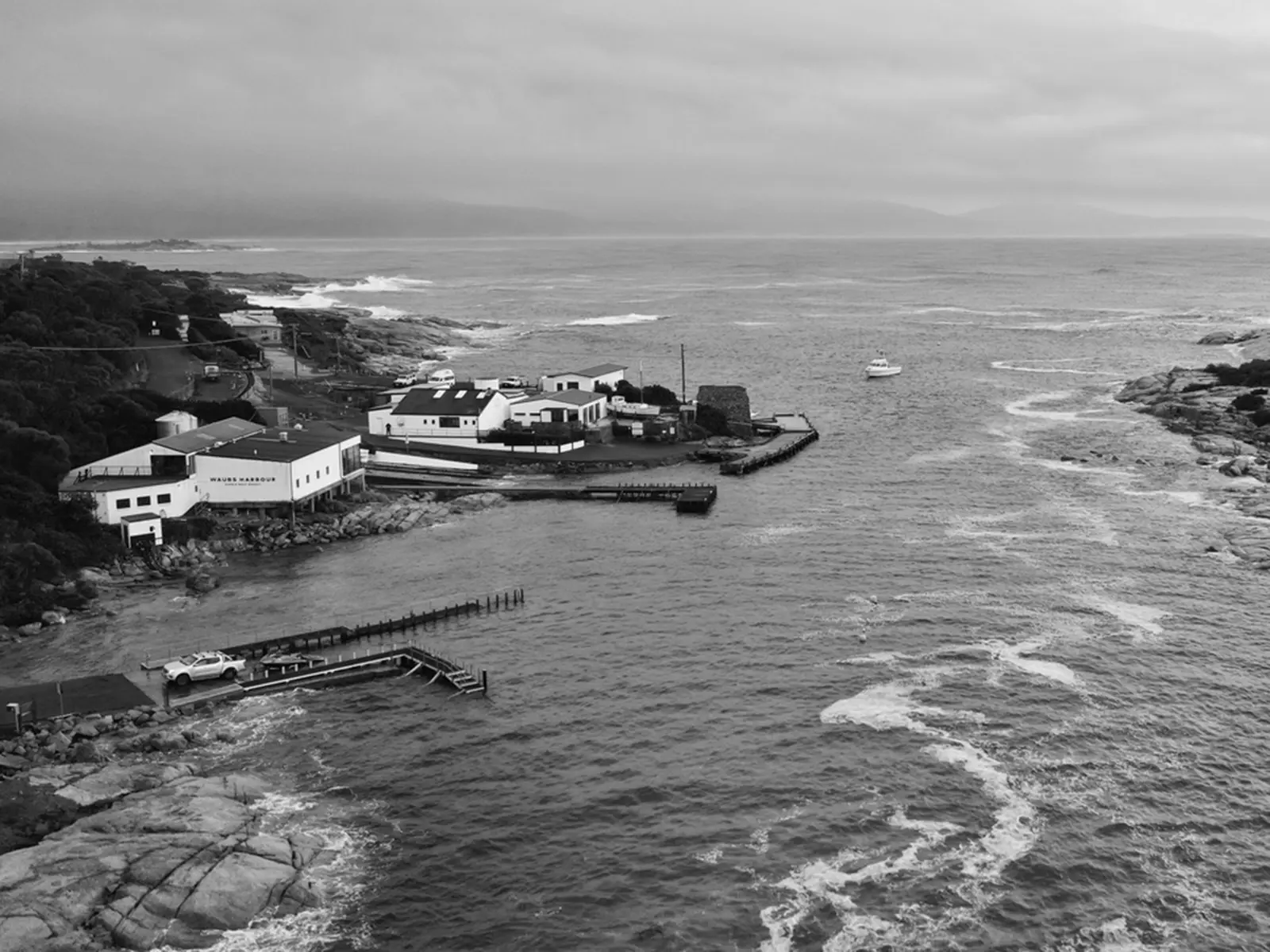 A grouping of waterfront buildings sit on a piece of land jutting out into a small bay.