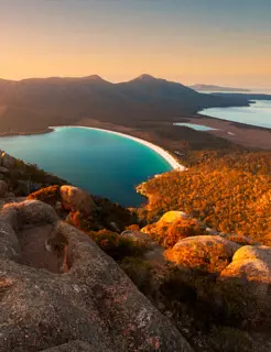 Ariel of Wineglass Bay, a traveller stands on a rock looking at the view.