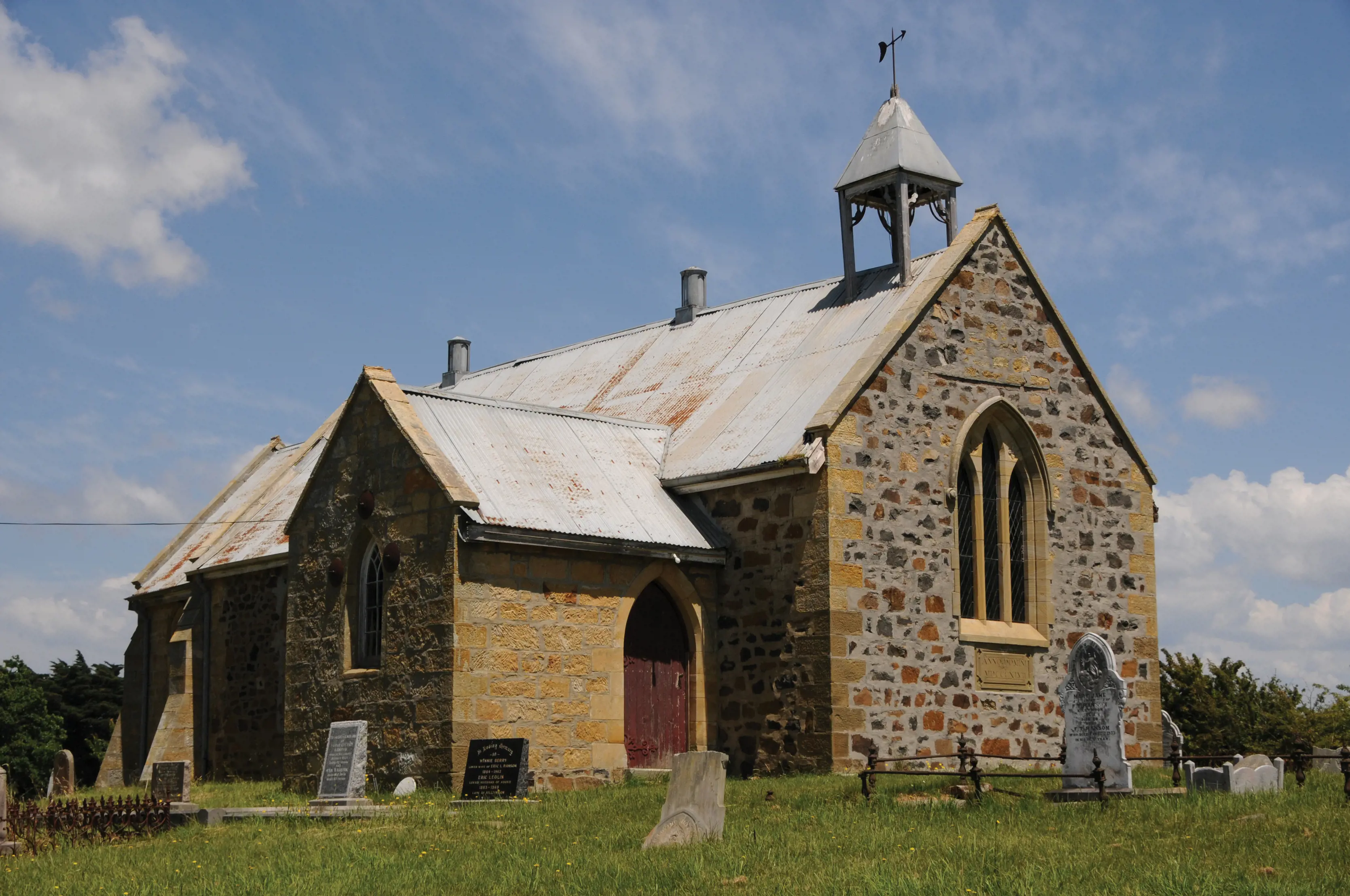 Old Christ Church in a field of grass. Two tone brick with a bell tower on top. 