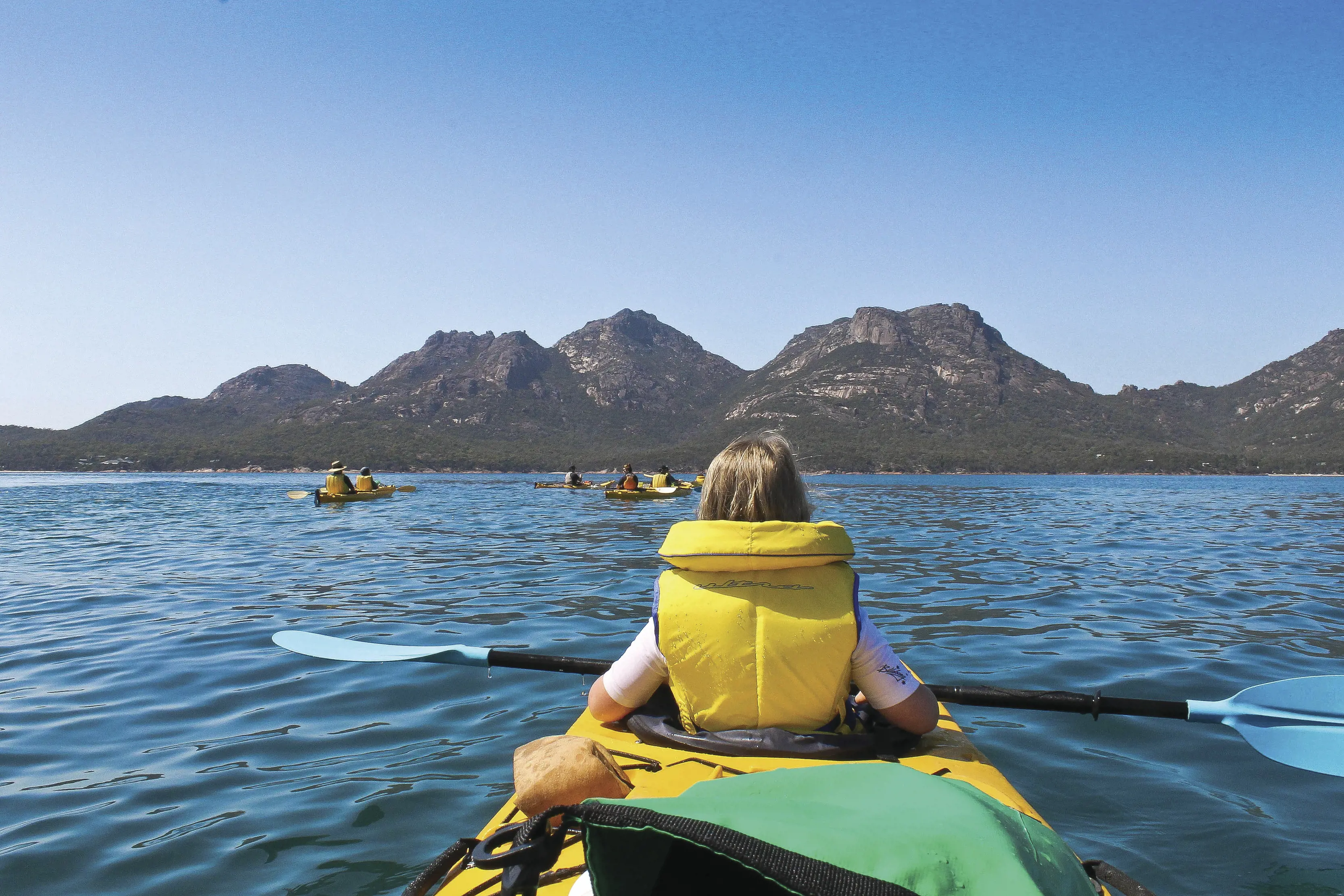 Two people paddle boarding on the water in Coles Bay. 