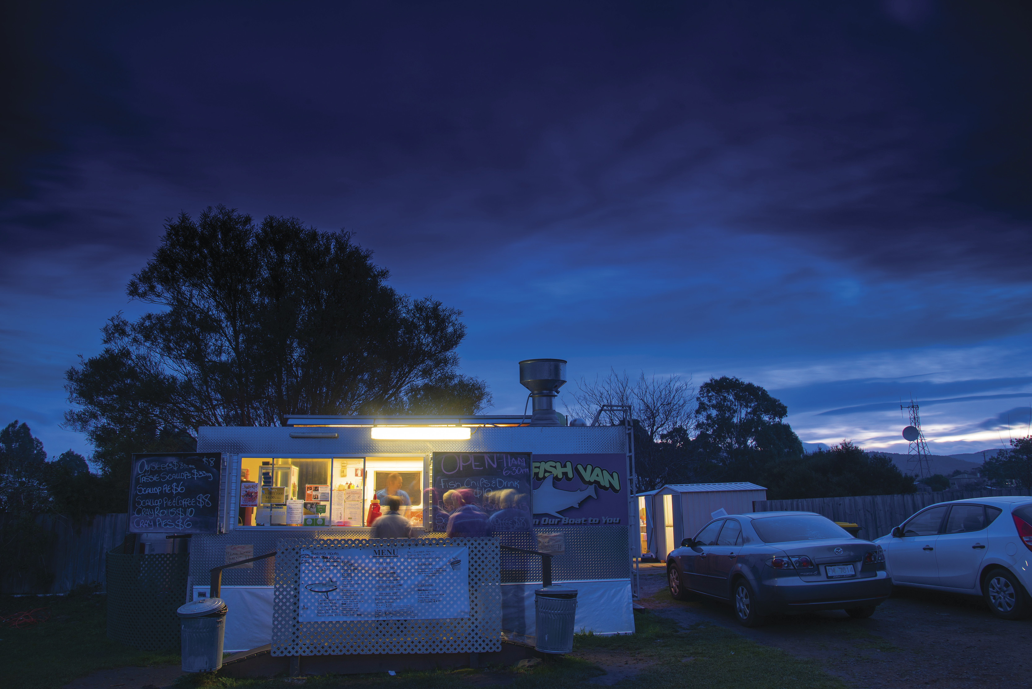 People queing at The Fish Van, Triabunna, with dark blue evening skies.
