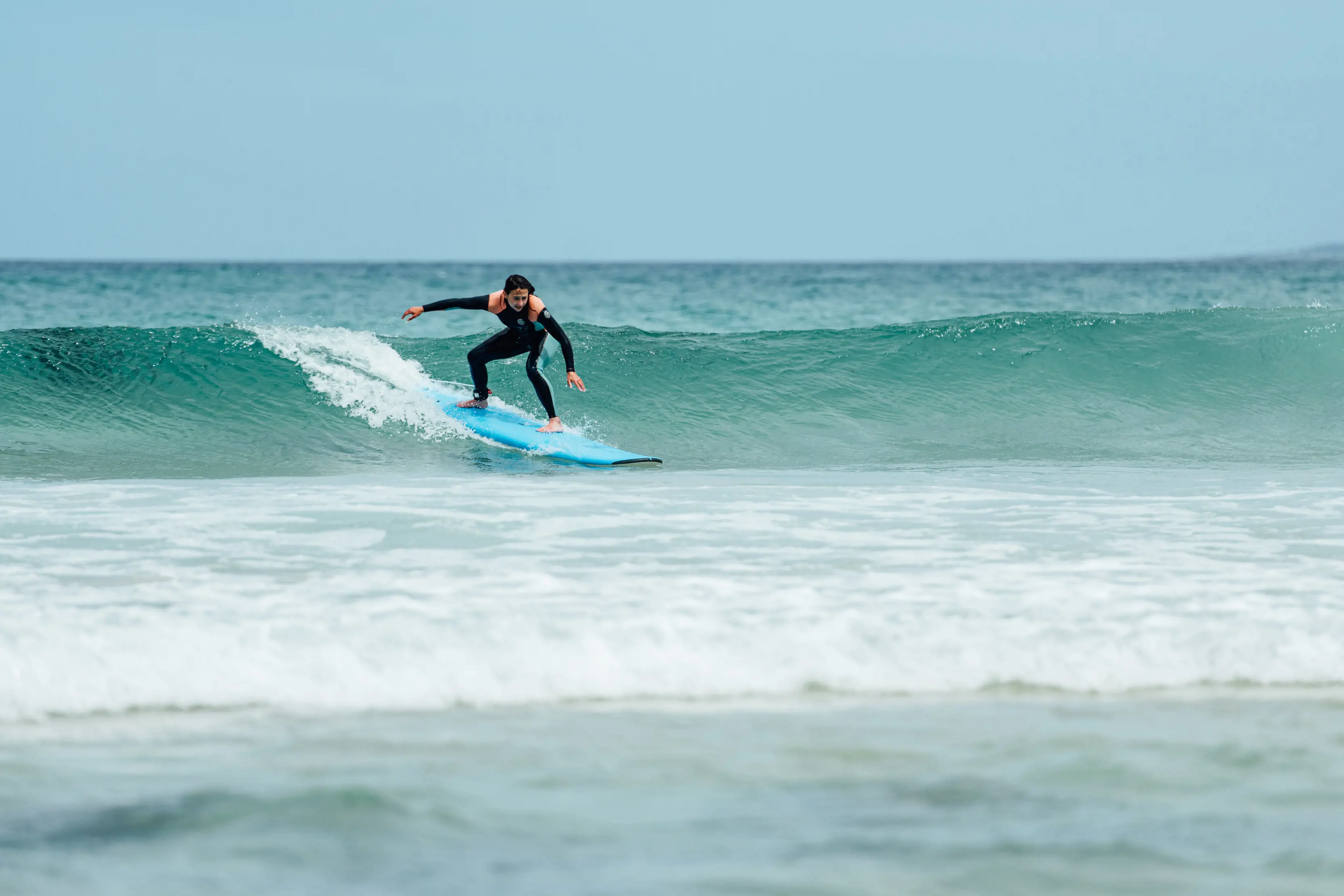 A man enjoys a surf lesson with 42 South Surf School, casting a wave at Scamander.