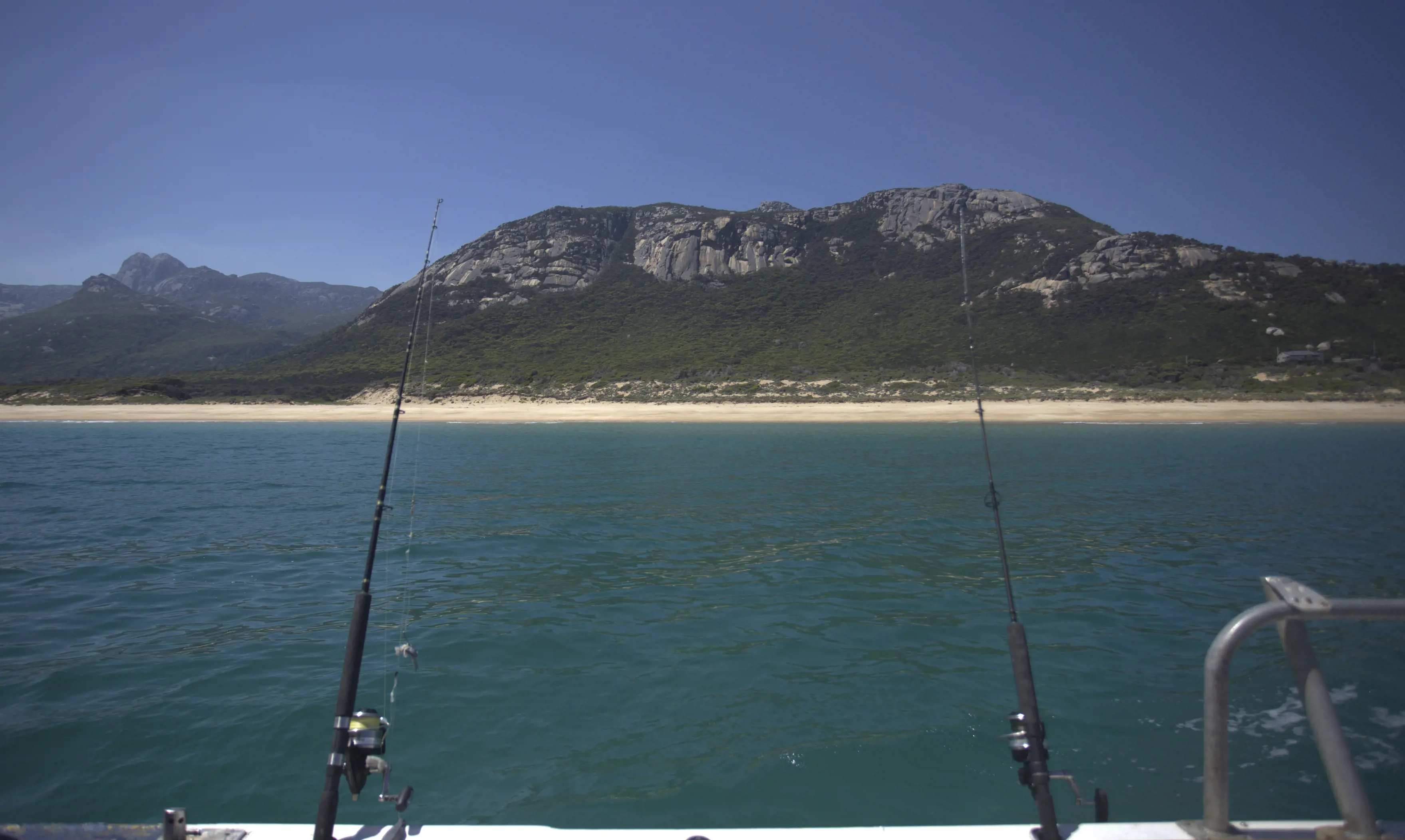 Image taken from boat of two fishing rods facing towards the coast of flinders Island.