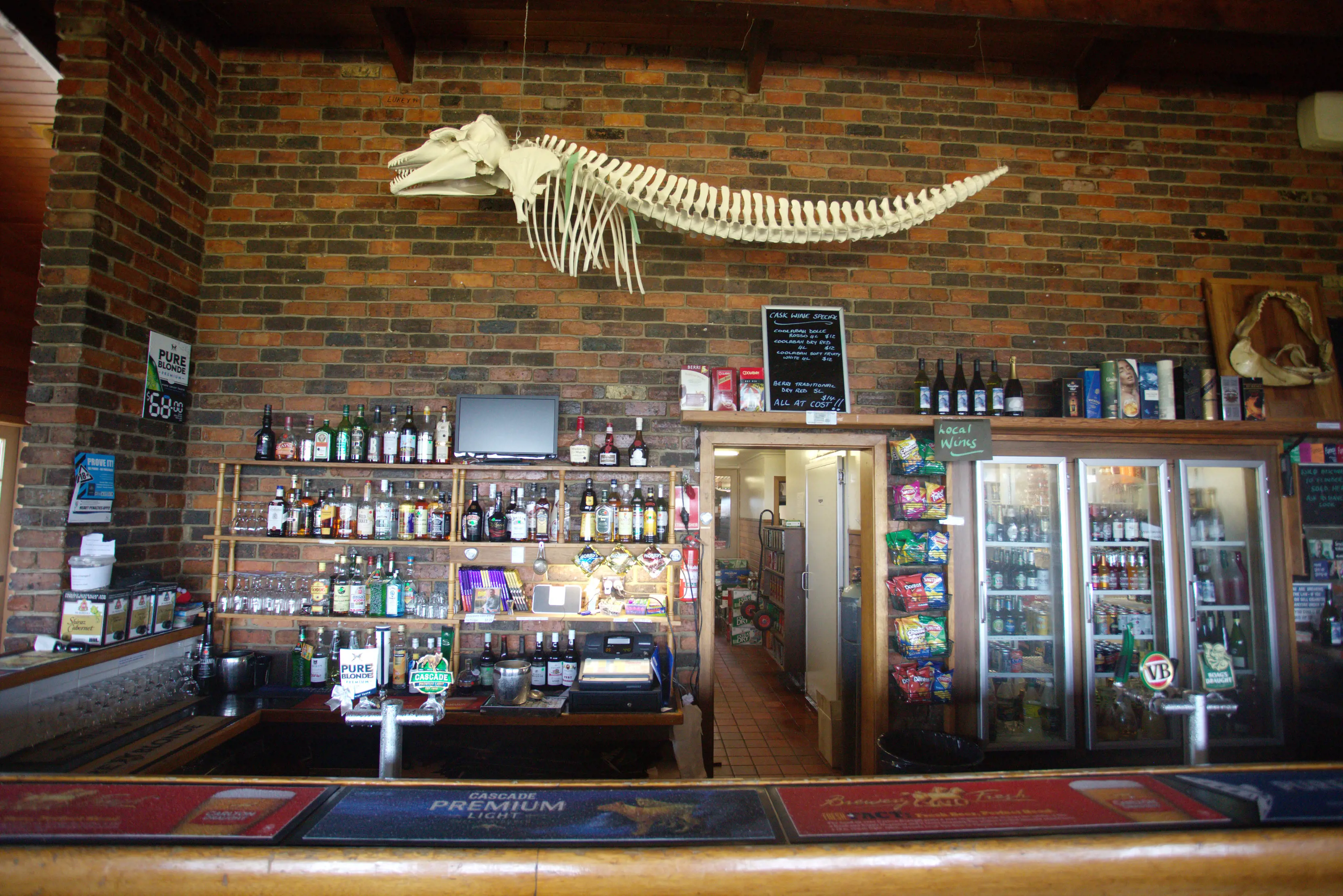 Image of inside Furneaux Tavern, fridges containing alcohol and old brick walls with a large ocean animal's skeleton hanging up.