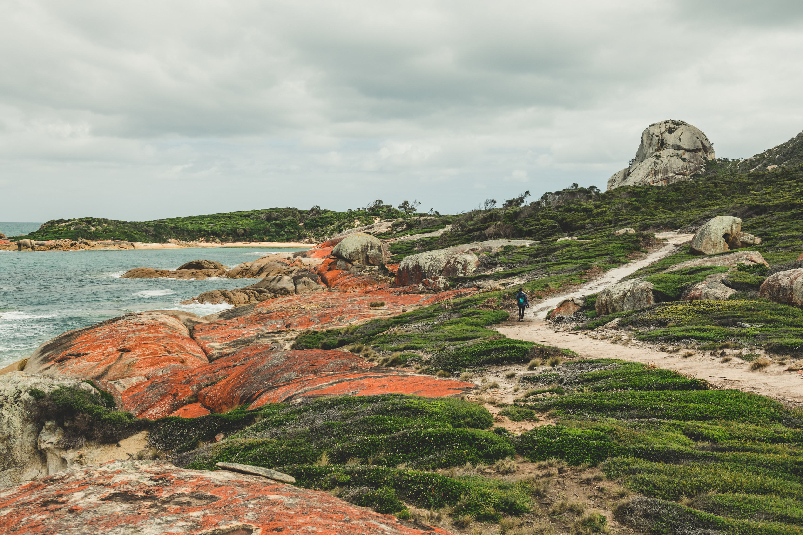 A surreal landscape of greens, oranges and blues. Person walking along Old Mans Head rock, Flinders Trail.