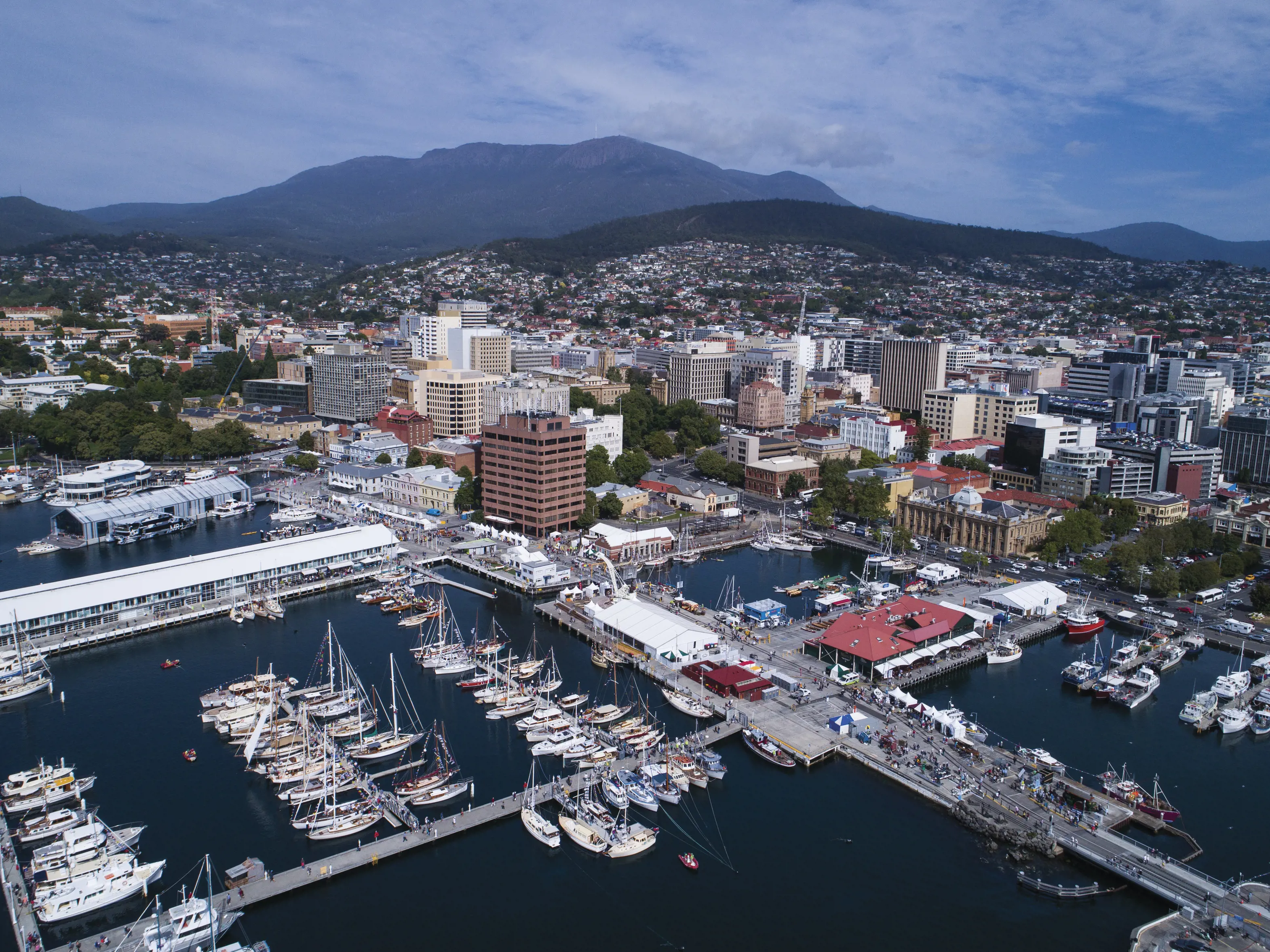 Aerial view of Hobart's marina, skyline and mountains in the background.