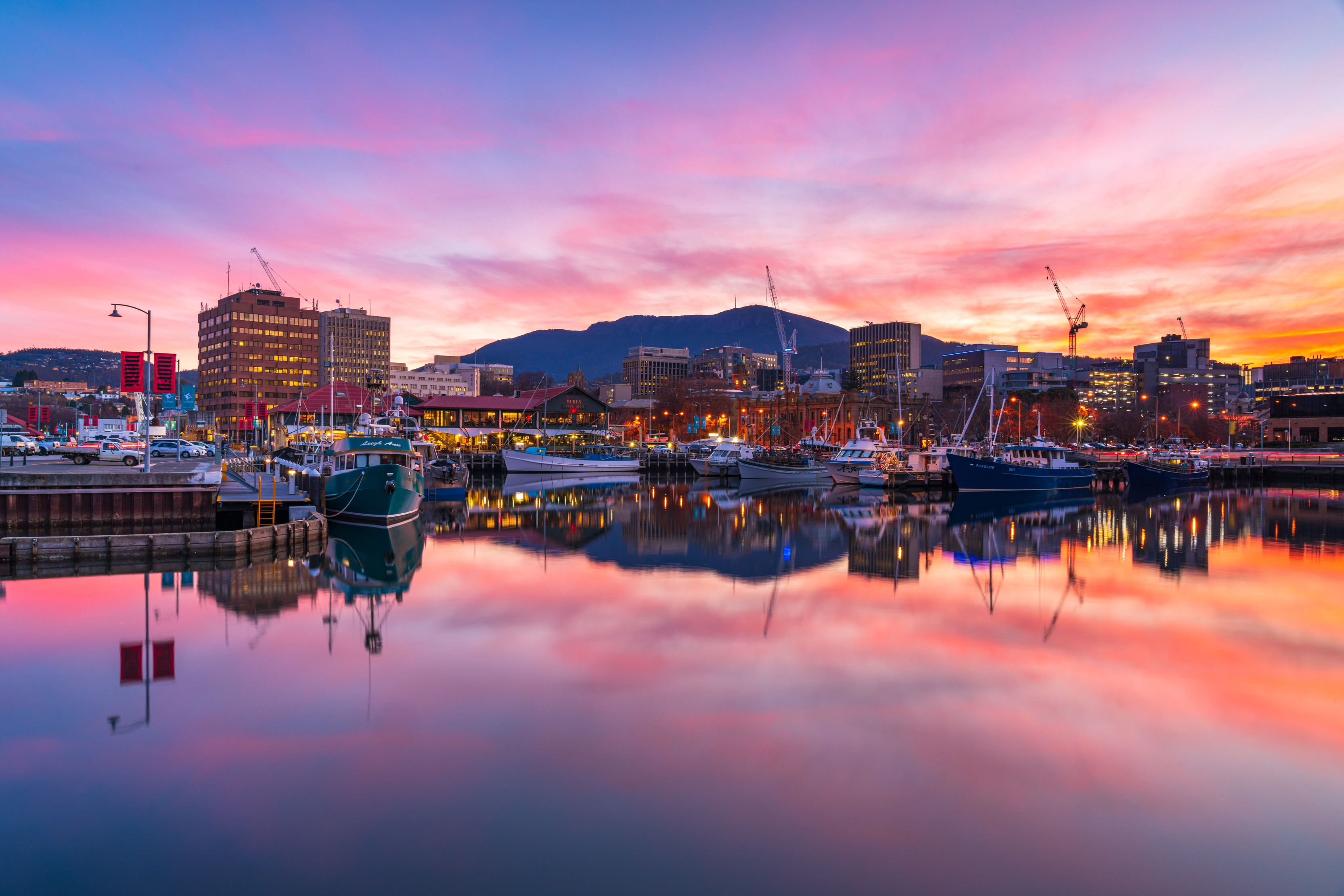 Hobart waterfront at sunset. Hues of pink, purple and orange hitting the skyline and water 