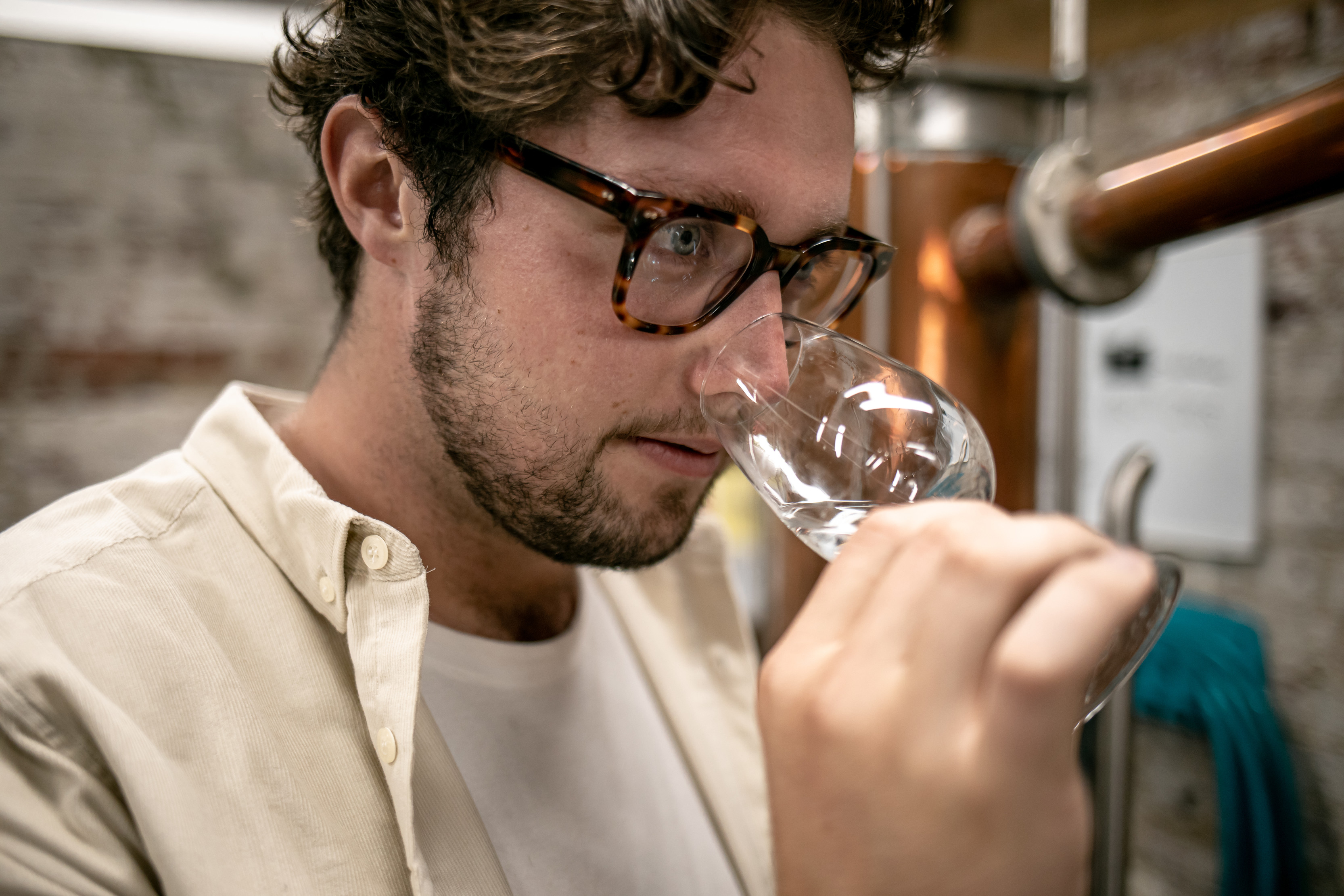 A person smells a glass filled with a sample of whiskey. Battery Point Distillery, Hobart.
