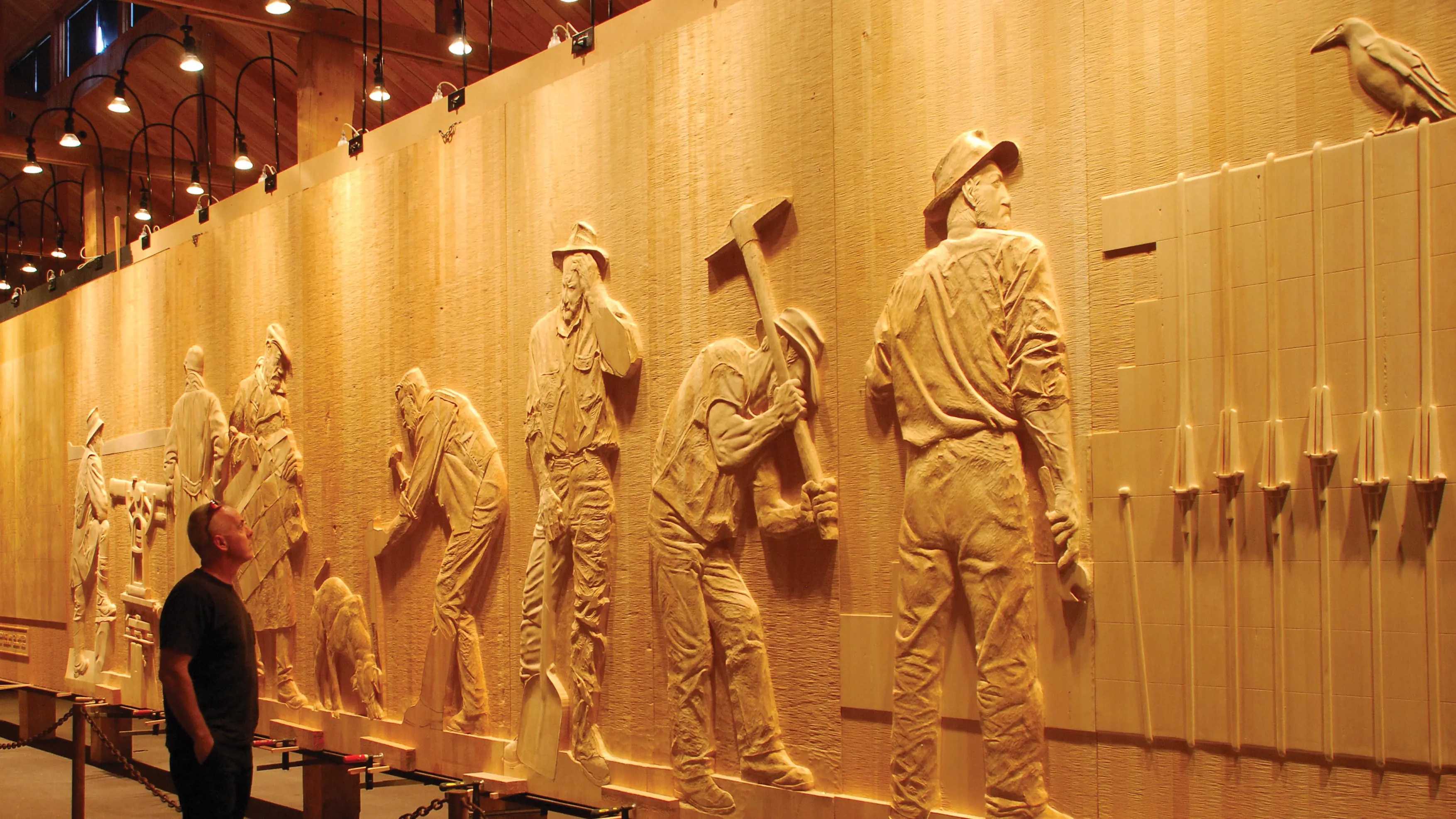 A traveller looks at The Wall in the Wilderness, a sculpture carved from wood panels. The panels tell the history of the Central Highlands region - with the indigenous people, the pioneering timber harvesters, pastoralists, miners and Hydro workers.