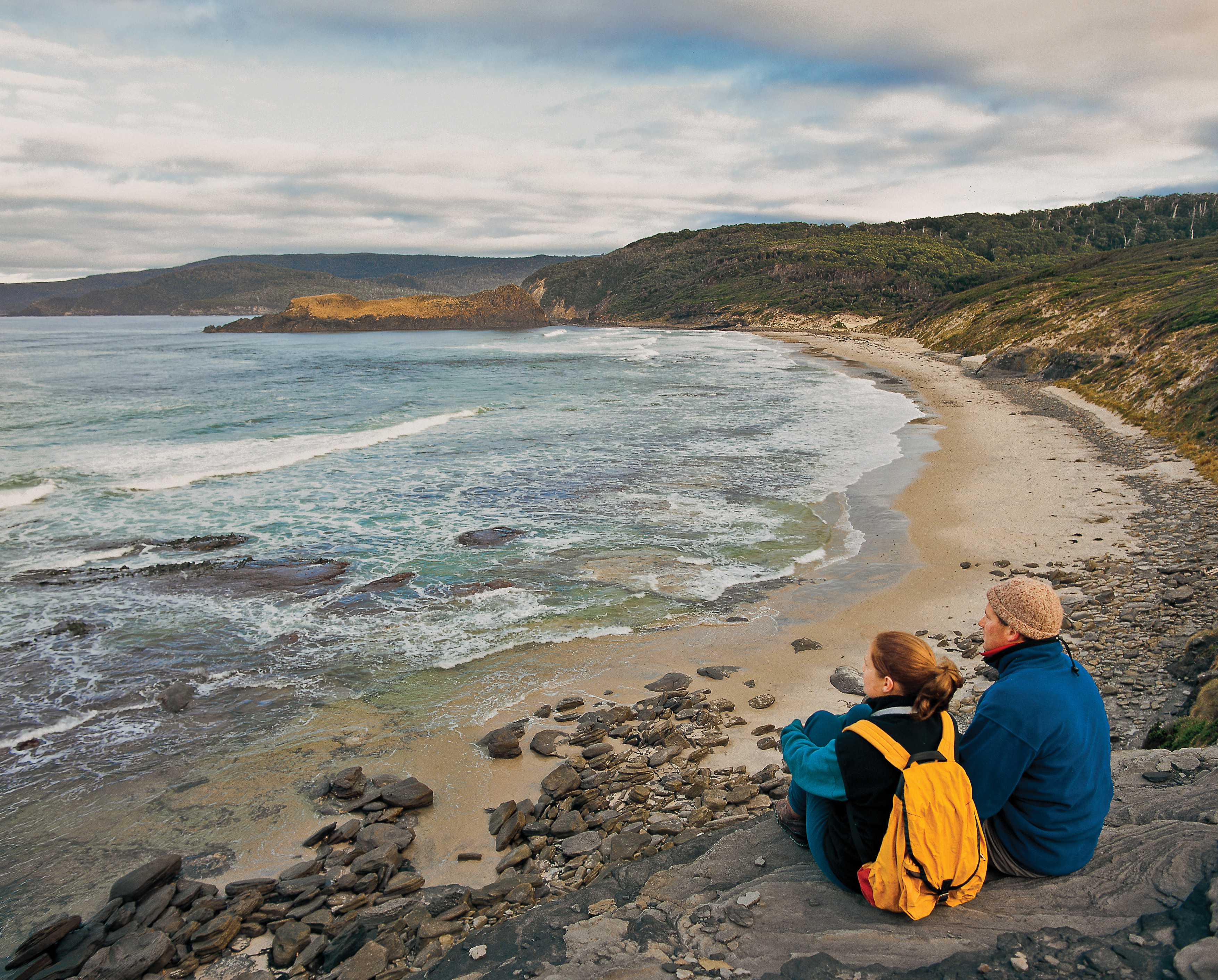 Breathtaking wide angle image of a couple sitting down and looking over South Cape Bay Beach.