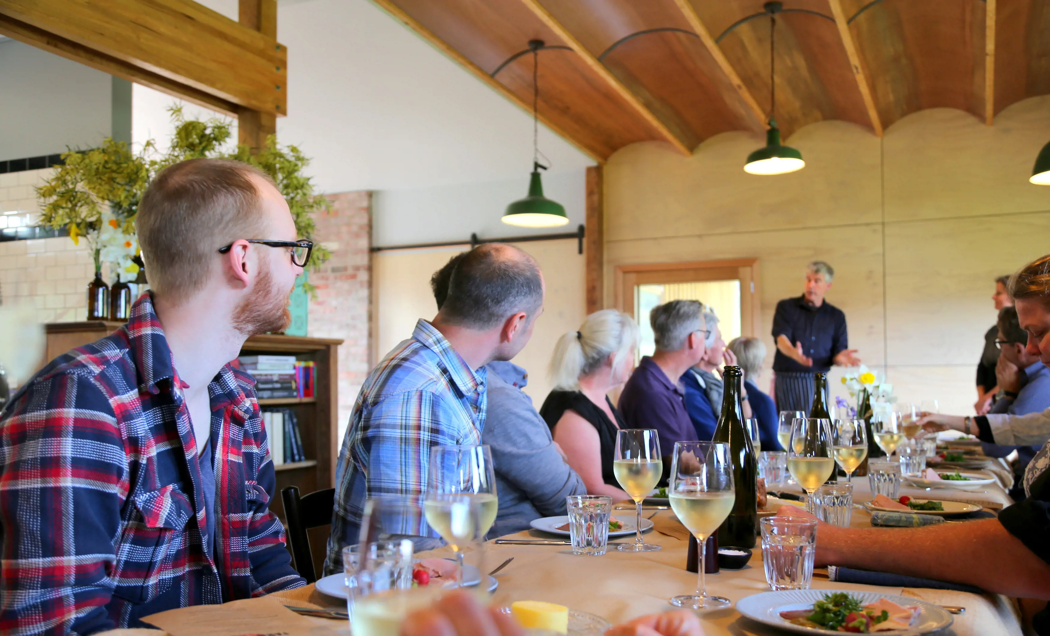 Group of people eating and drinking wine around a table at the Fat Pig Farm.